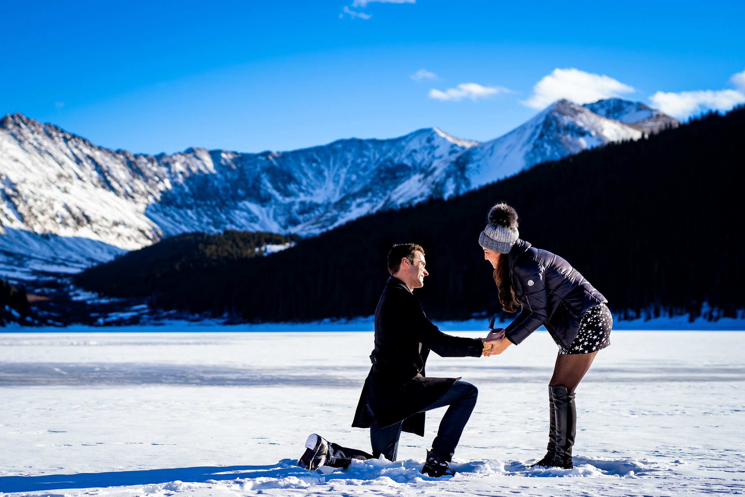 Man proposes to girlfriend while standing on a frozen lake with snowcapped mountains in the background, Engagement Session, Engagement Photos, Engagement Photos Inspiration, Engagement Photography, Engagement Photographer, Winter Engagement Photos, Proposal Photos, Proposal Photographer, Proposal Photography, Winter Proposal, Mountain Proposal, Proposal Inspiration, Summit County engagement session, Summit County engagement photos, Summit County engagement photography, Summit County engagement photographer, Summit County engagement inspiration, Colorado engagement session, Colorado engagement photos, Colorado engagement photography, Colorado engagement photographer, Colorado engagement inspiration, Clinton Gulch Engagement