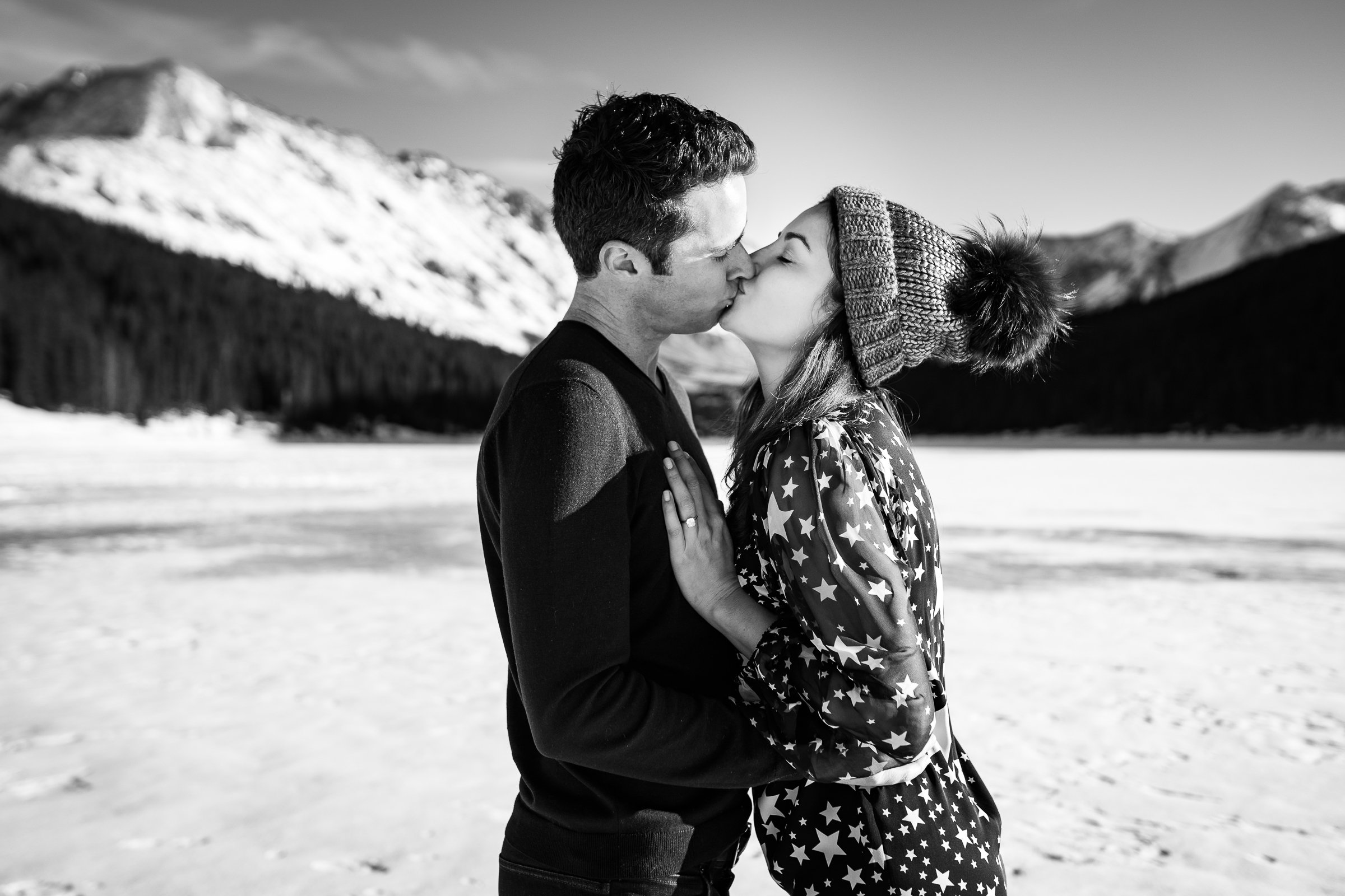 Newly engaged couple celebrate their proposal with a kiss on a frozen lake with snowcapped mountains in the background, Engagement Session, Engagement Photos, Engagement Photos Inspiration, Engagement Photography, Engagement Photographer, Winter Engagement Photos, Proposal Photos, Proposal Photographer, Proposal Photography, Winter Proposal, Mountain Proposal, Proposal Inspiration, Summit County engagement session, Summit County engagement photos, Summit County engagement photography, Summit County engagement photographer, Summit County engagement inspiration, Colorado engagement session, Colorado engagement photos, Colorado engagement photography, Colorado engagement photographer, Colorado engagement inspiration, Clinton Gulch Engagement