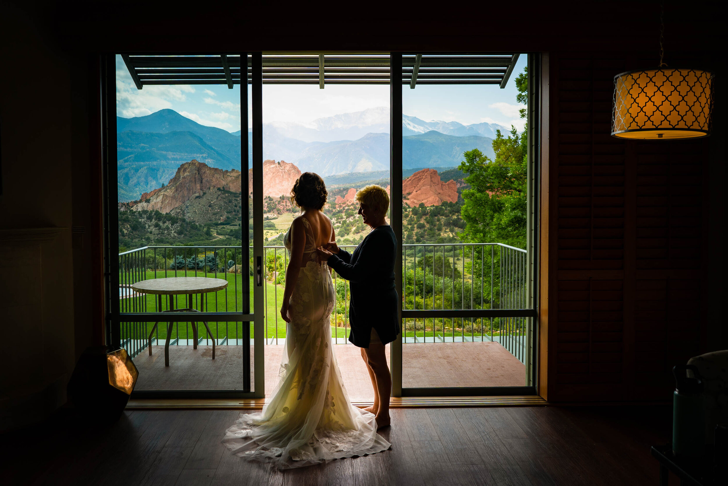 Bride's mom helps her into her wedding gown with the Garden of the Gods Park in the background, wedding photos, wedding photography, wedding photographer, wedding inspiration, wedding photo inspiration, wedding portraits, wedding ceremony, wedding reception, mountain wedding, Garden of the Gods wedding, Garden of the Gods Club & Resort wedding, Garden of the Gods Club & Resort wedding photos, Garden of the Gods Club & Resort wedding photography, Garden of the Gods Club & Resort wedding photographer, Garden of the Gods Club & Resort wedding inspiration, Garden of the Gods Club & Resort wedding venue, Colorado Springs wedding, Colorado Springs wedding photos,  Colorado Springs wedding photography, Colorado Springs wedding photographer, Colorado wedding, Colorado wedding photos, Colorado wedding photography, Colorado wedding photographer, Colorado mountain wedding, Colorado wedding inspiration