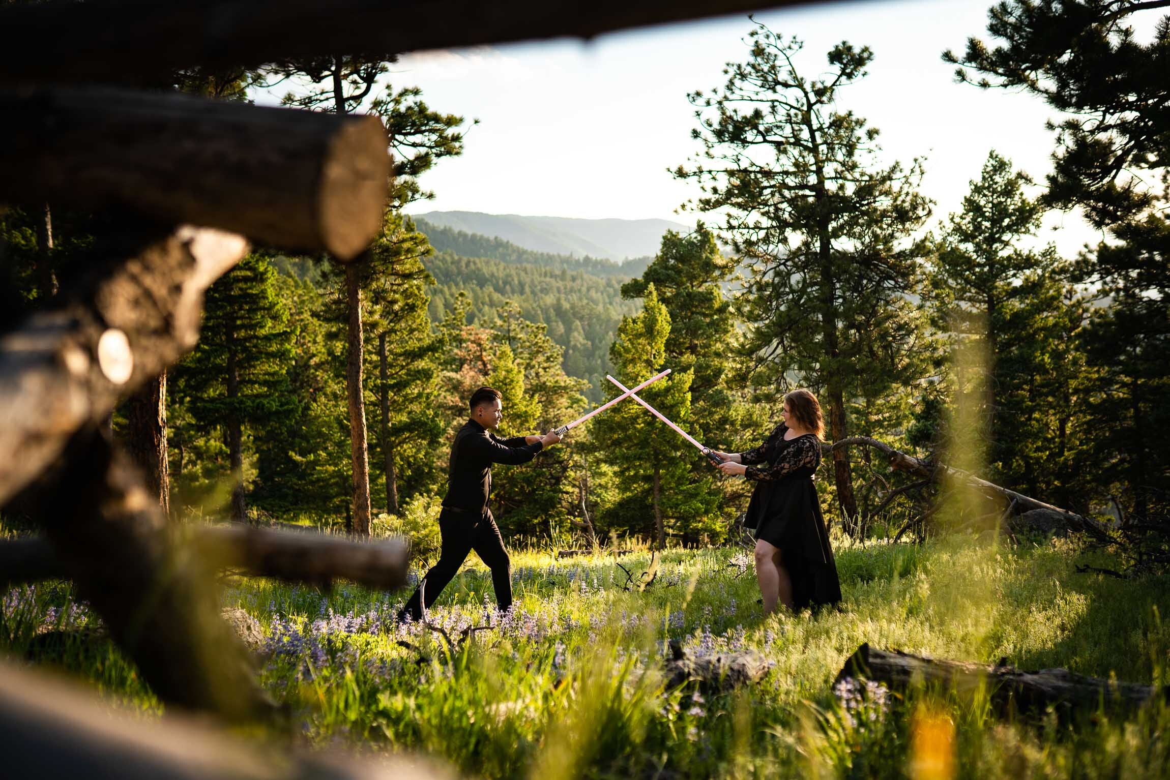 Engaged couple jumps into cosplay with their light sabers in the forest during golden hour, Engagement Session, Engagement Photos, Engagement Photos Inspiration, Engagement Photography, Engagement Photographer, Summer Engagement Photos, Mountain Engagement Photos, Lost Gulch Overlook engagement session, Lost Gulch Overlook engagement photos, Lost Gulch Overlook engagement photography, Lost Gulch Overlook engagement photographer, Lost Gulch Overlook  engagement inspiration, Boulder engagement session, Boulder engagement photos, Boulder engagement photography, Boulder engagement photographer, Boulder engagement inspiration, Colorado engagement session, Colorado engagement photos, Colorado engagement photography, Colorado engagement photographer, Colorado engagement inspiration

