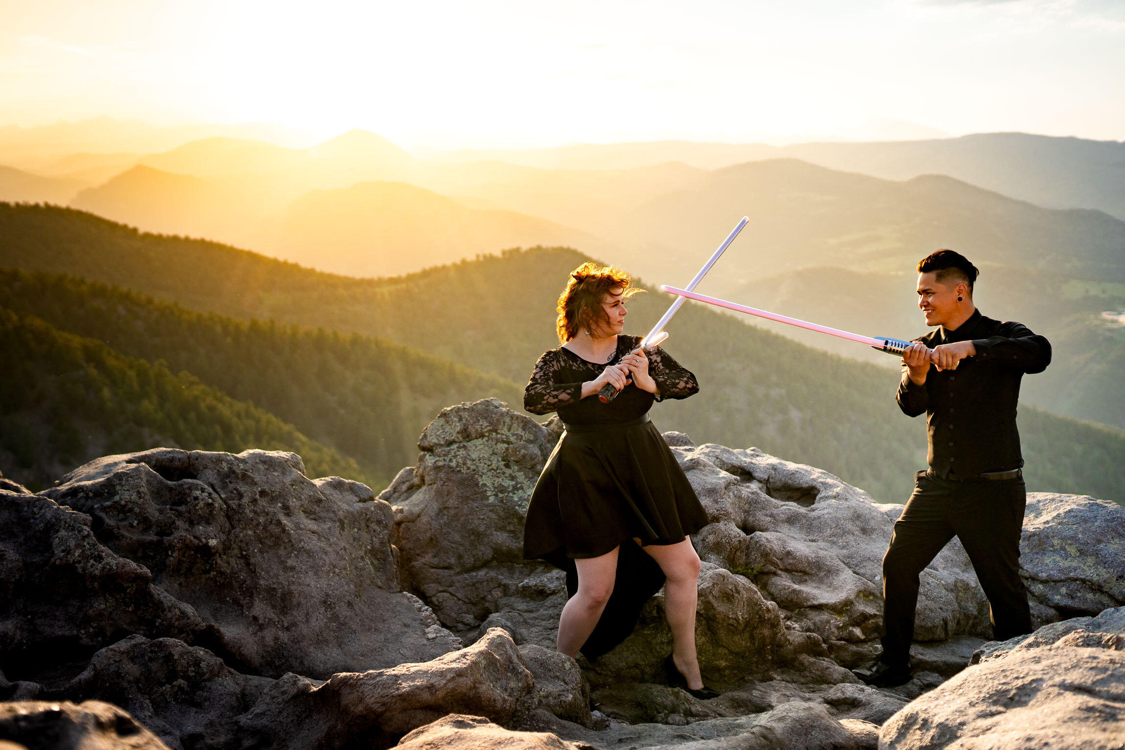 Engaged couple jumps into cosplay with their light sabers on a rocky ledge overlooking the mountains during golden hour, Engagement Session, Engagement Photos, Engagement Photos Inspiration, Engagement Photography, Engagement Photographer, Summer Engagement Photos, Mountain Engagement Photos, Lost Gulch Overlook engagement session, Lost Gulch Overlook engagement photos, Lost Gulch Overlook engagement photography, Lost Gulch Overlook engagement photographer, Lost Gulch Overlook  engagement inspiration, Boulder engagement session, Boulder engagement photos, Boulder engagement photography, Boulder engagement photographer, Boulder engagement inspiration, Colorado engagement session, Colorado engagement photos, Colorado engagement photography, Colorado engagement photographer, Colorado engagement inspiration