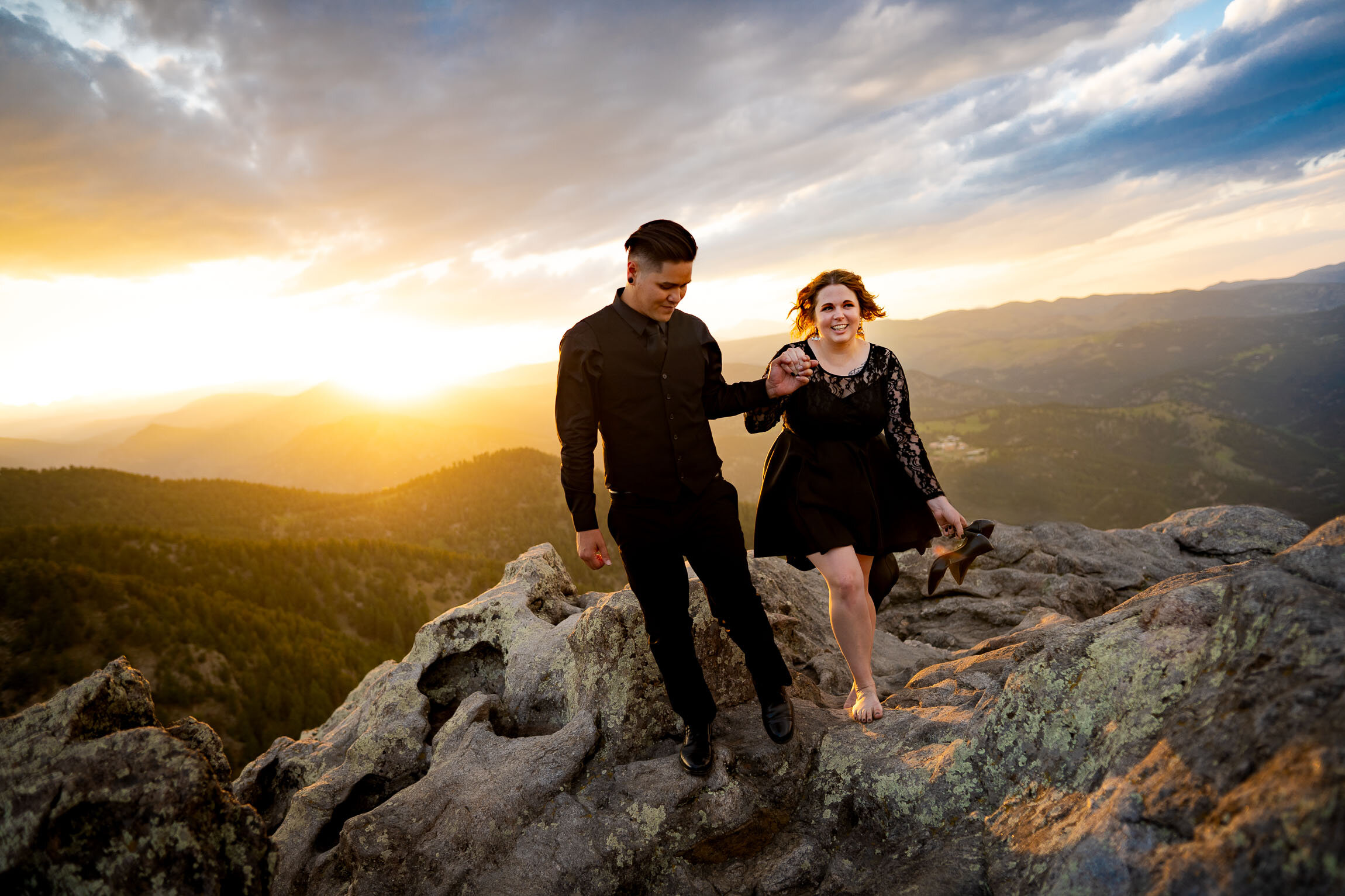 Engaged couple holds hands and watches the sun set from rocky ledge overlooking the mountains, Engagement Session, Sunset Engagement photos, Engagement Photos, Engagement Photos Inspiration, Engagement Photography, Engagement Photographer, Summer Engagement Photos, Mountain Engagement Photos, Lost Gulch Overlook engagement session, Lost Gulch Overlook engagement photos, Lost Gulch Overlook engagement photography, Lost Gulch Overlook engagement photographer, Lost Gulch Overlook  engagement inspiration, Boulder engagement session, Boulder engagement photos, Boulder engagement photography, Boulder engagement photographer, Boulder engagement inspiration, Colorado engagement session, Colorado engagement photos, Colorado engagement photography, Colorado engagement photographer, Colorado engagement inspiration