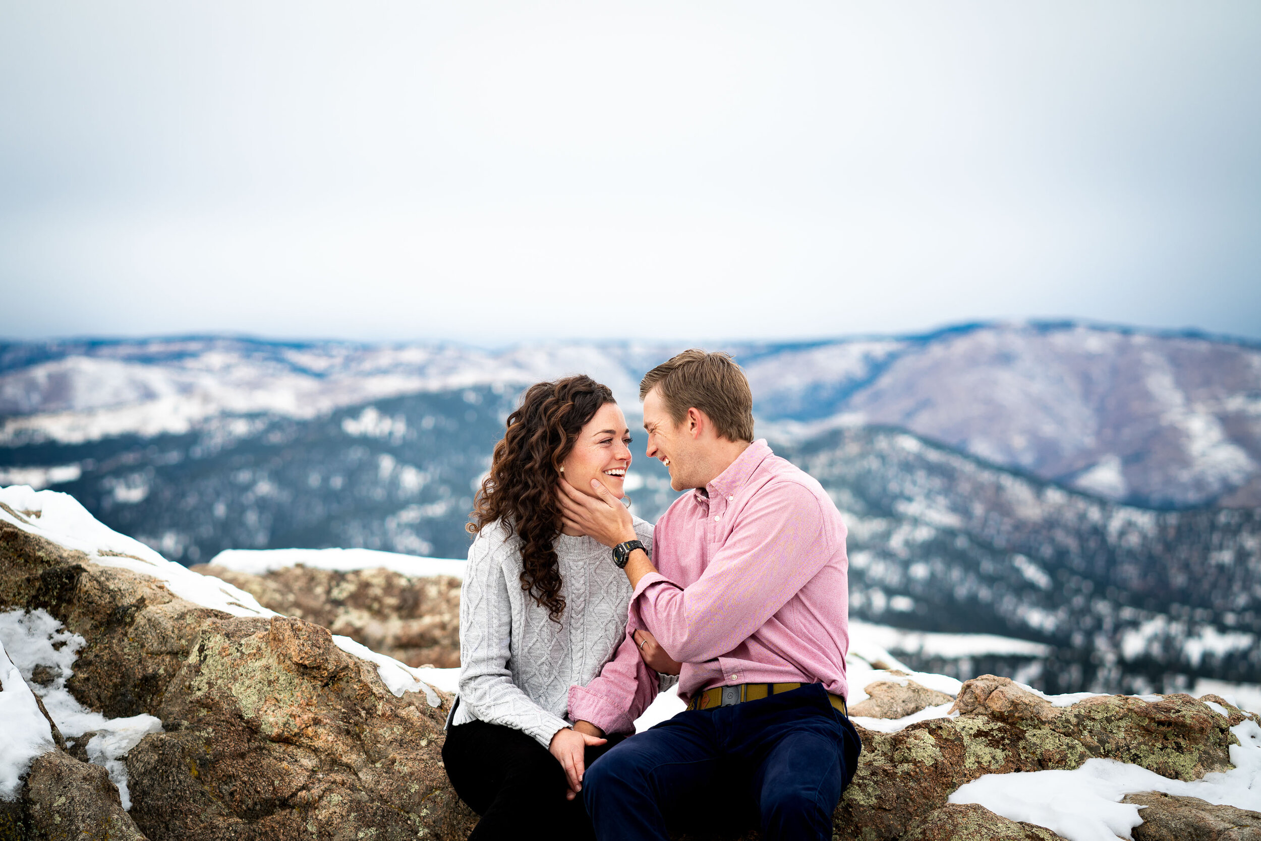 Engaged couple poses for portraits on a rocky ledge overlooking the snow-capped Rocky Mountains in the distance, Engagement Session, Engagement Photos, Engagement Photos Inspiration, Engagement Photography, Engagement Photographer, Winter Engagement Photos, Mountain Engagement Photos, Lost Gulch Overlook engagement session, Lost Gulch Overlook engagement photos, Lost Gulch Overlook engagement photography, Lost Gulch Overlook engagement photographer, Lost Gulch Overlook  engagement inspiration, Boulder engagement session, Boulder engagement photos, Boulder engagement photography, Boulder engagement photographer, Boulder engagement inspiration, Colorado engagement session, Colorado engagement photos, Colorado engagement photography, Colorado engagement photographer, Colorado engagement inspiration