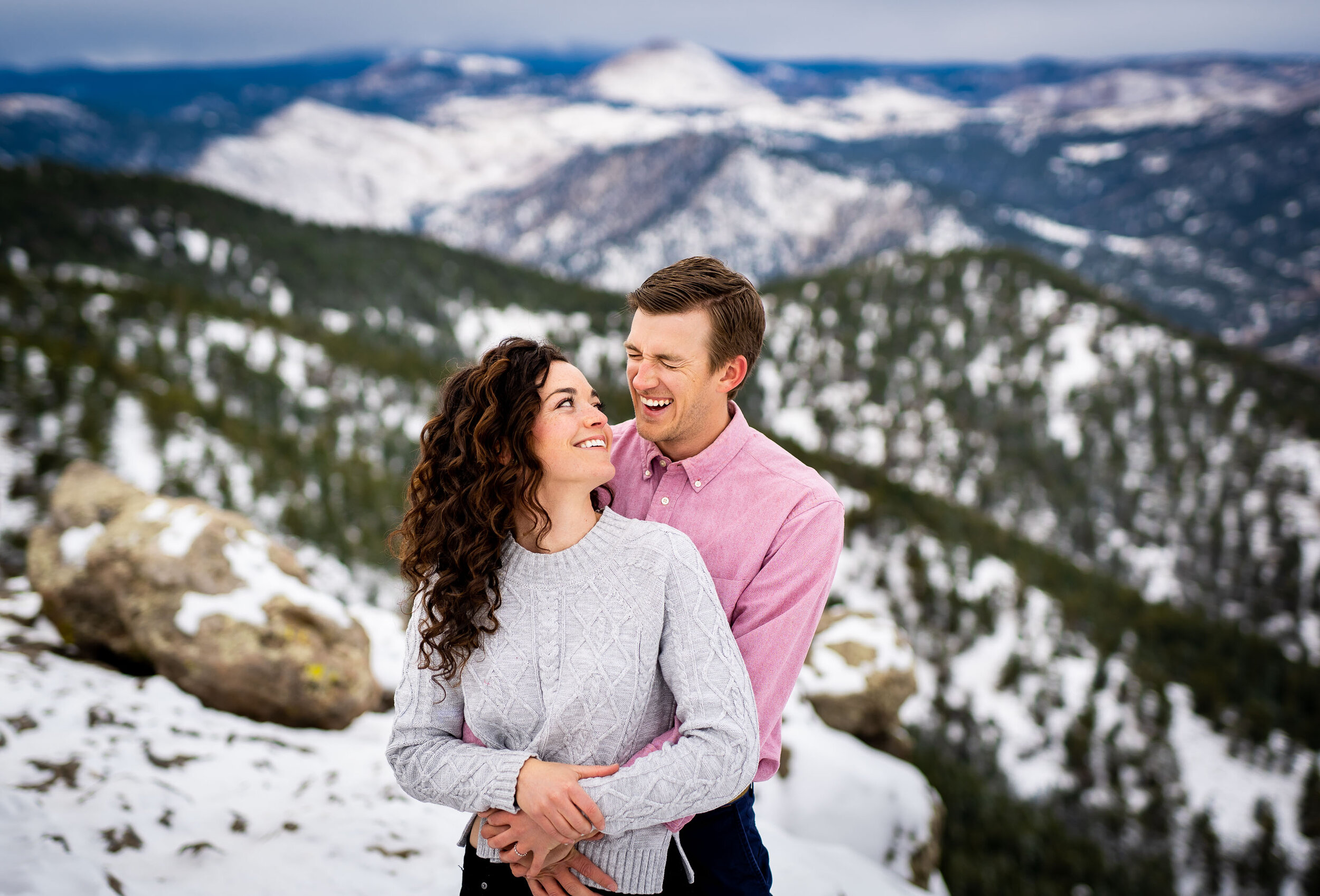 Engaged couple poses for portraits on a rocky ledge overlooking the snow-capped Rocky Mountains in the distance, Engagement Session, Engagement Photos, Engagement Photos Inspiration, Engagement Photography, Engagement Photographer, Winter Engagement Photos, Mountain Engagement Photos, Lost Gulch Overlook engagement session, Lost Gulch Overlook engagement photos, Lost Gulch Overlook engagement photography, Lost Gulch Overlook engagement photographer, Lost Gulch Overlook  engagement inspiration, Boulder engagement session, Boulder engagement photos, Boulder engagement photography, Boulder engagement photographer, Boulder engagement inspiration, Colorado engagement session, Colorado engagement photos, Colorado engagement photography, Colorado engagement photographer, Colorado engagement inspiration