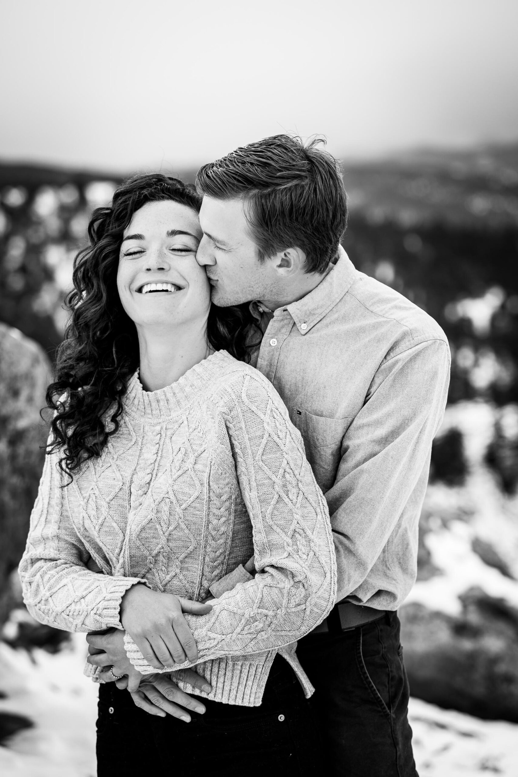 Engaged couple poses for portraits on a rocky ledge overlooking the snow-capped Rocky Mountains in the distance, Engagement Session, Engagement Photos, Engagement Photos Inspiration, Engagement Photography, Engagement Photographer, Winter Engagement Photos, Mountain Engagement Photos, Lost Gulch Overlook engagement session, Lost Gulch Overlook engagement photos, Lost Gulch Overlook engagement photography, Lost Gulch Overlook engagement photographer, Lost Gulch Overlook  engagement inspiration, Boulder engagement session, Boulder engagement photos, Boulder engagement photography, Boulder engagement photographer, Boulder engagement inspiration, Colorado engagement session, Colorado engagement photos, Colorado engagement photography, Colorado engagement photographer, Colorado engagement inspiration