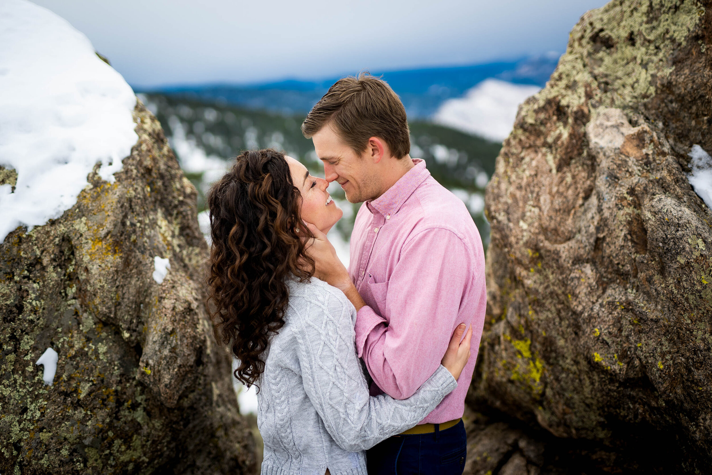 Engaged couple poses for portraits on a rocky ledge overlooking the snow-capped Rocky Mountains in the distance, Engagement Session, Engagement Photos, Engagement Photos Inspiration, Engagement Photography, Engagement Photographer, Winter Engagement Photos, Mountain Engagement Photos, Lost Gulch Overlook engagement session, Lost Gulch Overlook engagement photos, Lost Gulch Overlook engagement photography, Lost Gulch Overlook engagement photographer, Lost Gulch Overlook  engagement inspiration, Boulder engagement session, Boulder engagement photos, Boulder engagement photography, Boulder engagement photographer, Boulder engagement inspiration, Colorado engagement session, Colorado engagement photos, Colorado engagement photography, Colorado engagement photographer, Colorado engagement inspiration