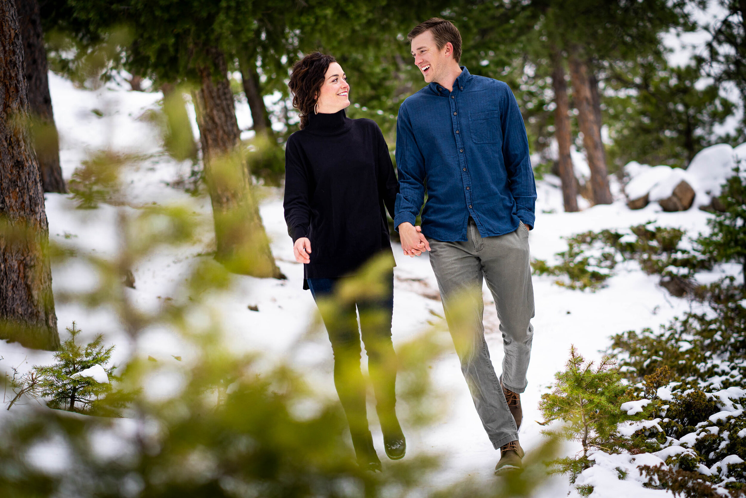 Engaged couple walks while holding hands in the snow in a dense evergreen mountain forest, Engagement Session, Engagement Photos, Engagement Photos Inspiration, Engagement Photography, Engagement Photographer, Winter Engagement Photos, Mountain Engagement Photos, Lost Gulch Overlook engagement session, Lost Gulch Overlook engagement photos, Lost Gulch Overlook engagement photography, Lost Gulch Overlook engagement photographer, Lost Gulch Overlook  engagement inspiration, Boulder engagement session, Boulder engagement photos, Boulder engagement photography, Boulder engagement photographer, Boulder engagement inspiration, Colorado engagement session, Colorado engagement photos, Colorado engagement photography, Colorado engagement photographer, Colorado engagement inspiration