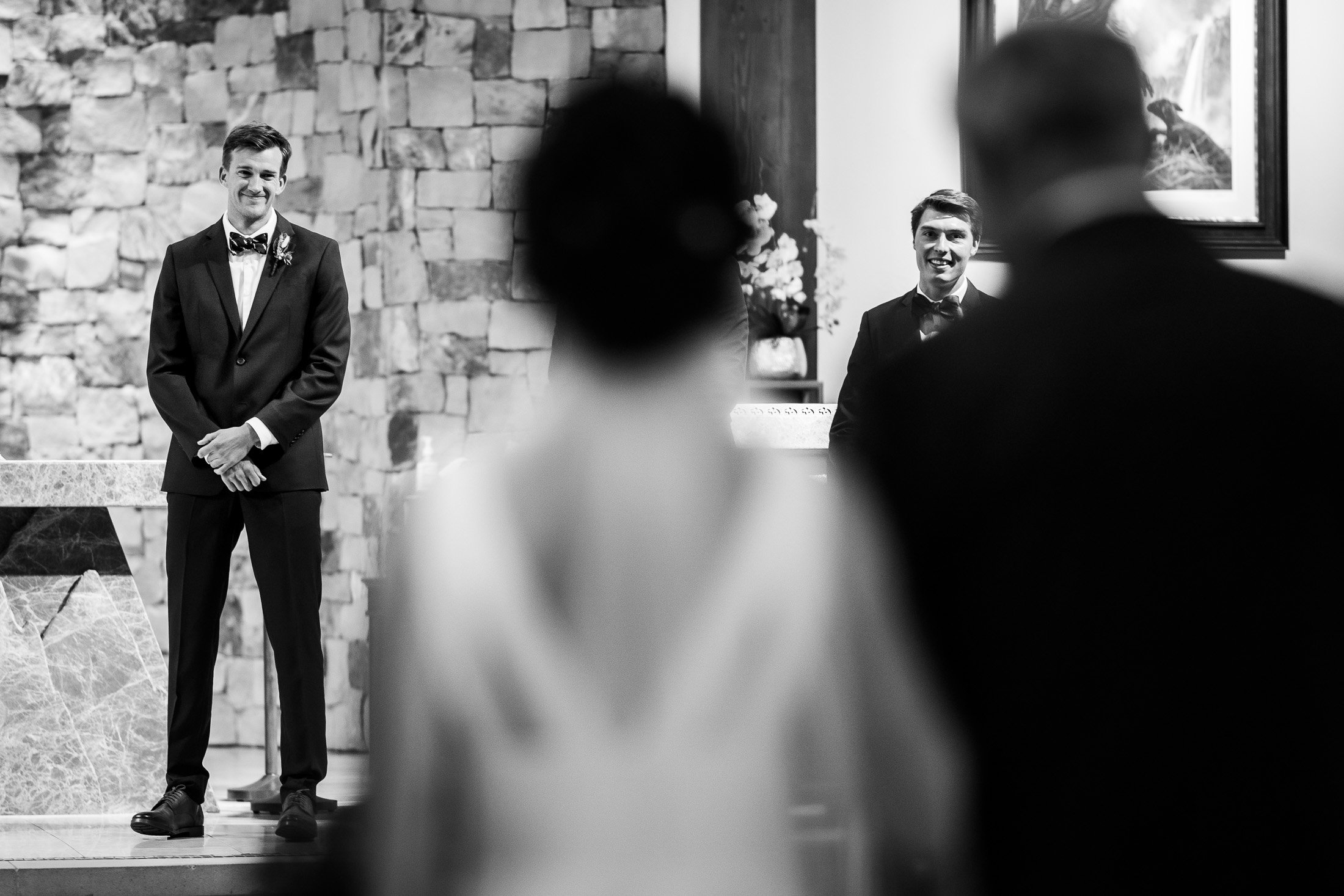 Groom reacts with a smile as the bride walks down the aisle during the processional during their wedding ceremony at the church, wedding, wedding photos, wedding photography, wedding photographer, wedding inspiration, wedding photo inspiration, wedding portraits, wedding ceremony, wedding reception, mountain wedding, Catholic Church wedding, Catholic Church wedding photos, Catholic Church wedding photography, Catholic Church wedding photographer, Catholic Church wedding inspiration, Catholic Church wedding venue, Steamboat Springs wedding, Steamboat Springs wedding photos, Steamboat Springs wedding photography, Steamboat Springs wedding photographer, Colorado wedding, Colorado wedding photos, Colorado wedding photography, Colorado wedding photographer, Colorado mountain wedding, Colorado wedding inspiration