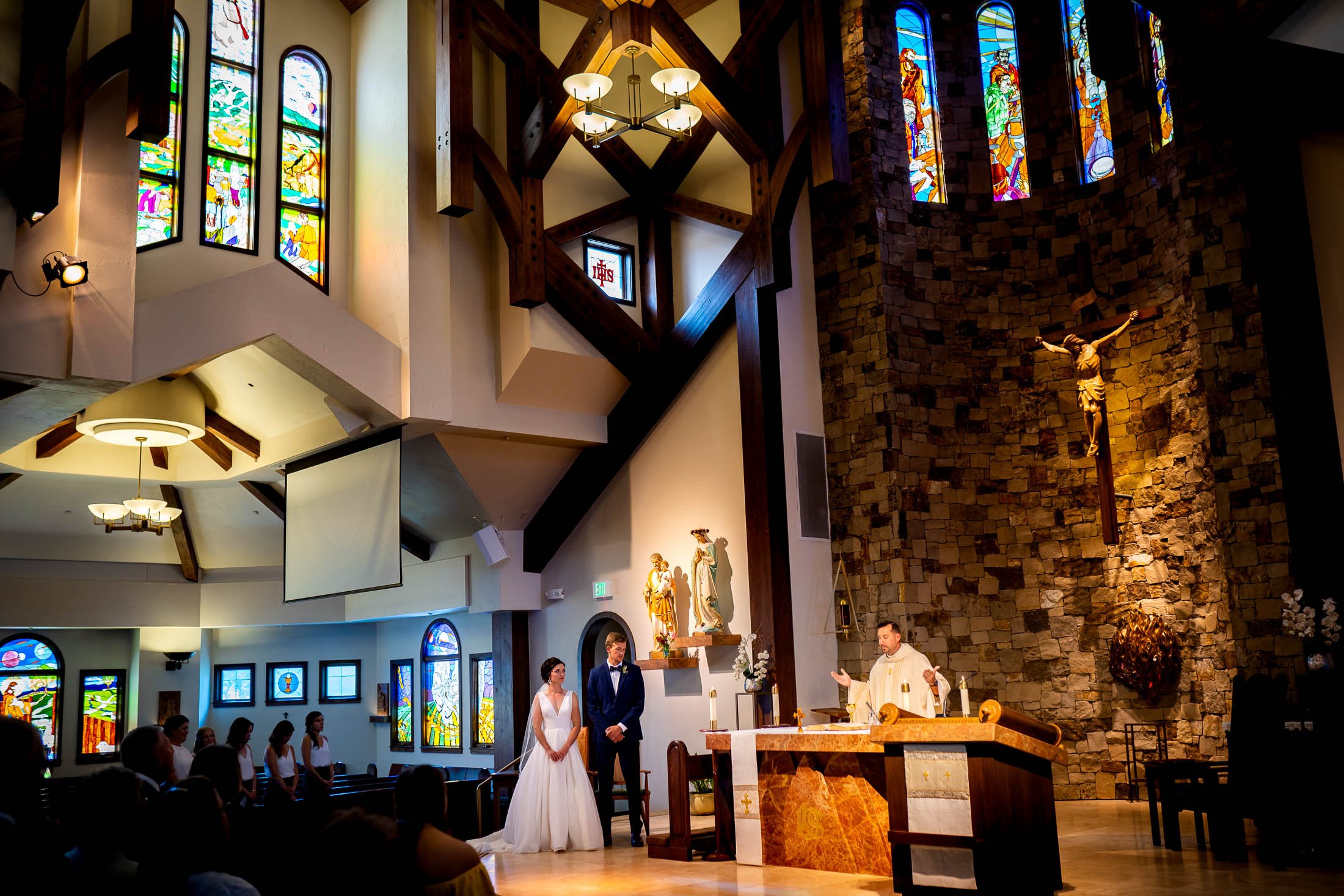 Bride and groom attend their catholic wedding ceremony at the church in a wide photography where you can see stained glass windows, wedding, wedding photos, wedding photography, wedding photographer, wedding inspiration, wedding photo inspiration, wedding portraits, wedding ceremony, wedding reception, mountain wedding, Catholic Church wedding, Catholic Church wedding photos, Catholic Church wedding photography, Catholic Church wedding photographer, Catholic Church wedding inspiration, Catholic Church wedding venue, Steamboat Springs wedding, Steamboat Springs wedding photos, Steamboat Springs wedding photography, Steamboat Springs wedding photographer, Colorado wedding, Colorado wedding photos, Colorado wedding photography, Colorado wedding photographer, Colorado mountain wedding, Colorado wedding inspiration