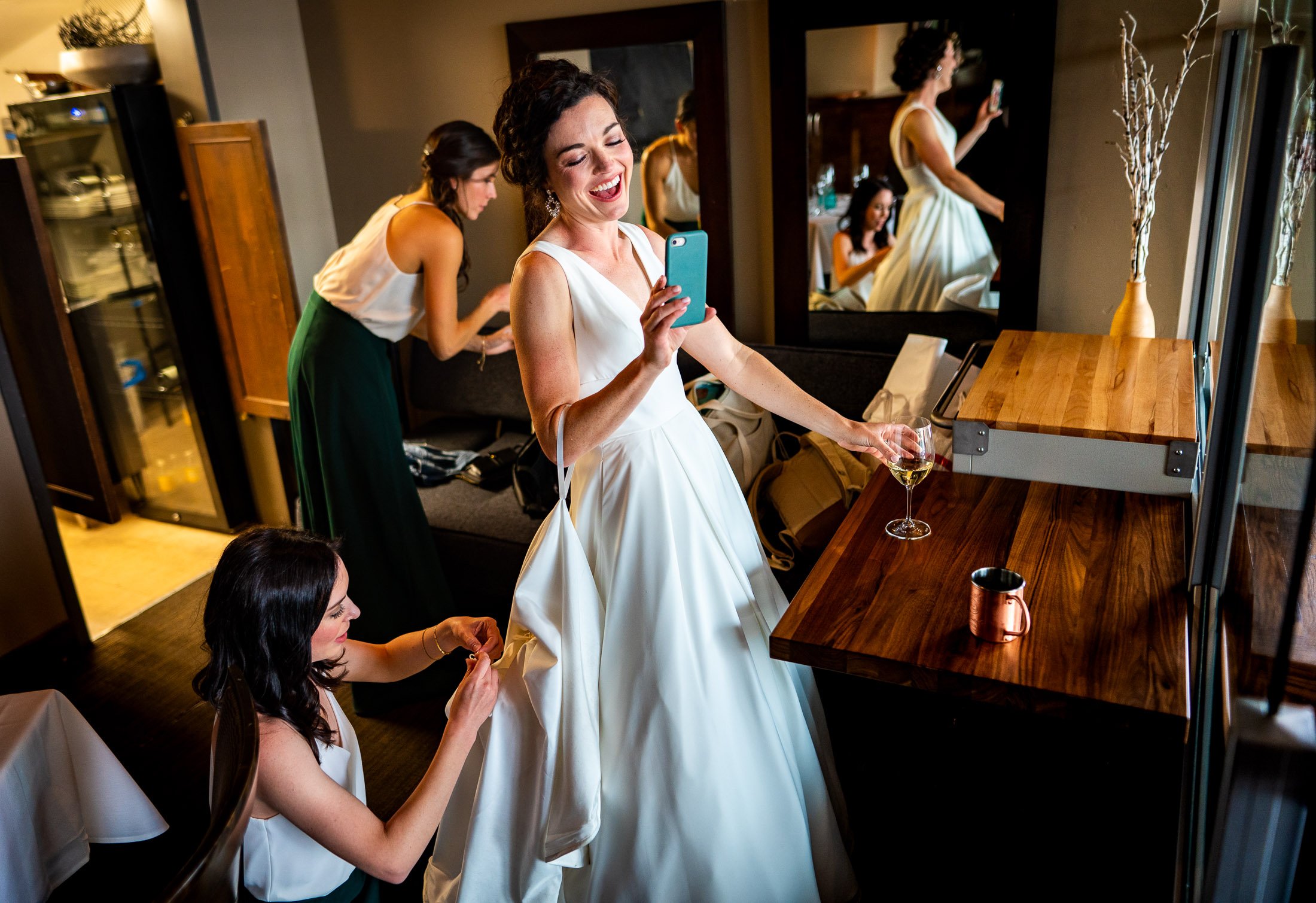 Bride talks with a friend via FaceTime as her dress is bustled, wedding, wedding photos, wedding photography, wedding photographer, wedding inspiration, wedding photo inspiration, wedding portraits, wedding ceremony, wedding reception, mountain wedding, Catholic Church wedding, Catholic Church wedding photos, Catholic Church wedding photography, Catholic Church wedding photographer, Catholic Church wedding inspiration, Catholic Church wedding venue, Steamboat Springs wedding, Steamboat Springs wedding photos, Steamboat Springs wedding photography, Steamboat Springs wedding photographer, Colorado wedding, Colorado wedding photos, Colorado wedding photography, Colorado wedding photographer, Colorado mountain wedding, Colorado wedding inspiration