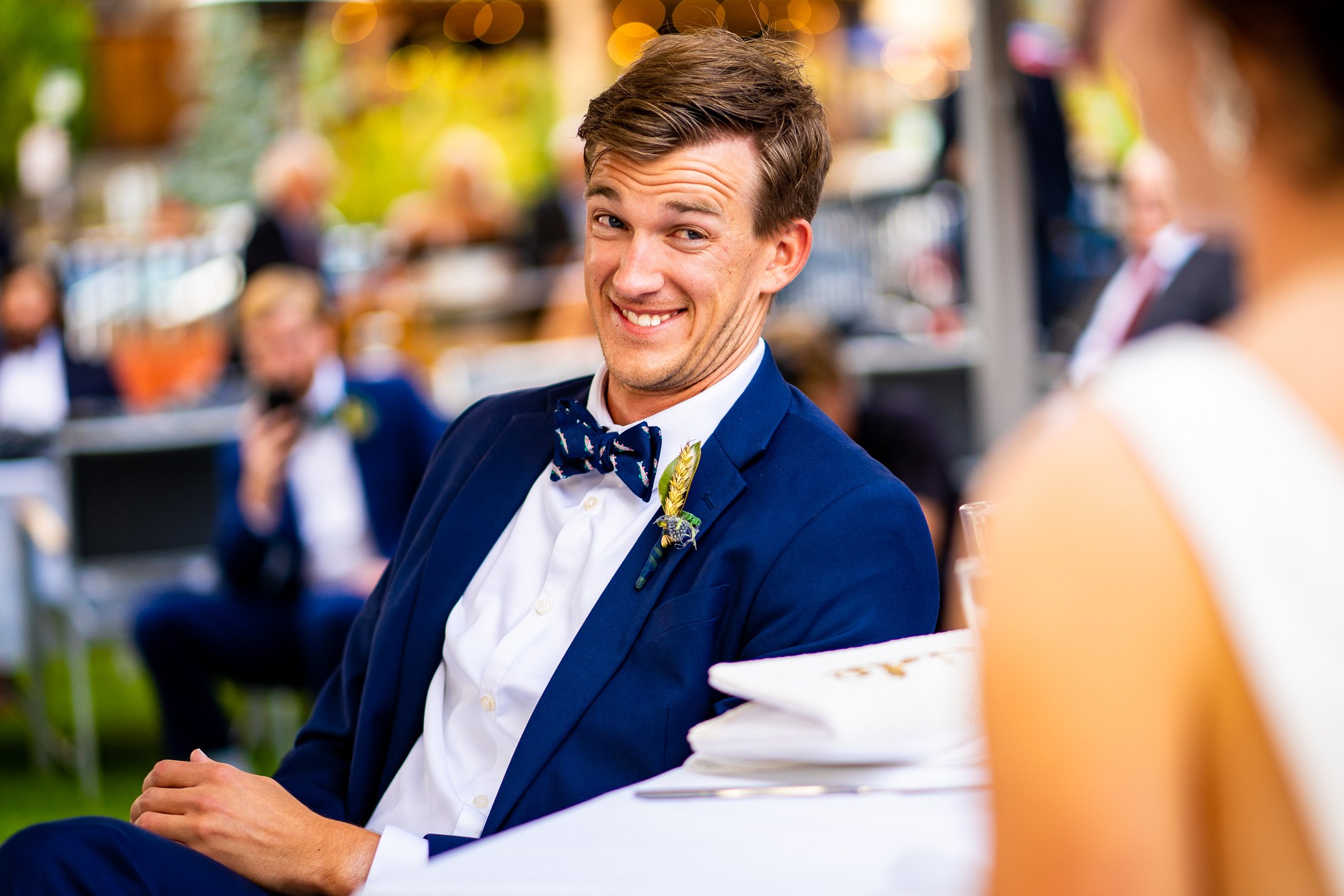 Bride and groom react to reception speeches while sitting on outdoor patio during the wedding reception, wedding, wedding photos, wedding photography, wedding photographer, wedding inspiration, wedding photo inspiration, wedding portraits, wedding ceremony, wedding reception, mountain wedding, Catholic Church wedding, Catholic Church wedding photos, Catholic Church wedding photography, Catholic Church wedding photographer, Catholic Church wedding inspiration, Catholic Church wedding venue, Steamboat Springs wedding, Steamboat Springs wedding photos, Steamboat Springs wedding photography, Steamboat Springs wedding photographer, Colorado wedding, Colorado wedding photos, Colorado wedding photography, Colorado wedding photographer, Colorado mountain wedding, Colorado wedding inspiration