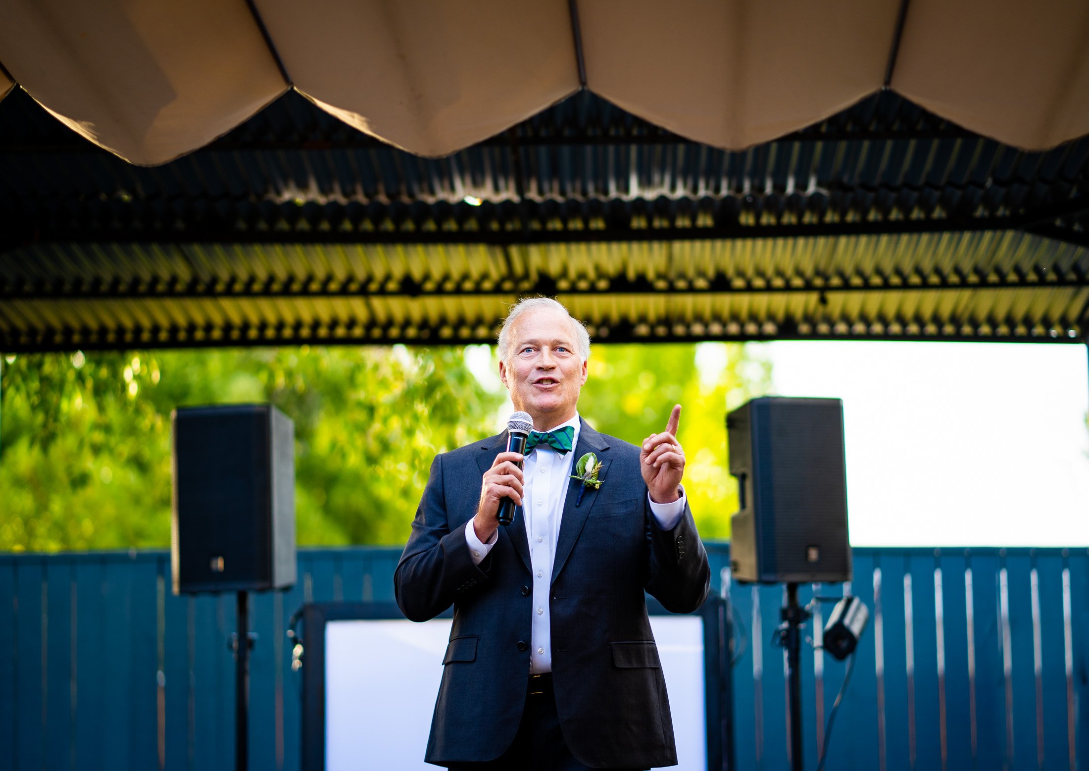 Father of the bride gives a speech while standing on an outdoor patio during the wedding reception, wedding, wedding photos, wedding photography, wedding photographer, wedding inspiration, wedding photo inspiration, wedding portraits, wedding ceremony, wedding reception, mountain wedding, Catholic Church wedding, Catholic Church wedding photos, Catholic Church wedding photography, Catholic Church wedding photographer, Catholic Church wedding inspiration, Catholic Church wedding venue, Steamboat Springs wedding, Steamboat Springs wedding photos, Steamboat Springs wedding photography, Steamboat Springs wedding photographer, Colorado wedding, Colorado wedding photos, Colorado wedding photography, Colorado wedding photographer, Colorado mountain wedding, Colorado wedding inspiration