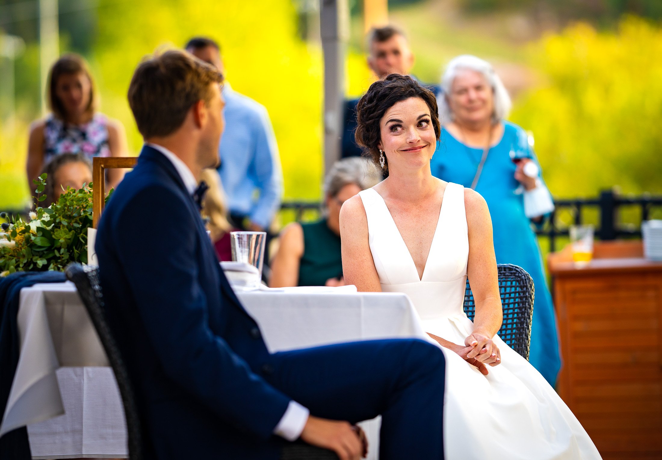 Bride and groom react to reception speeches while sitting on outdoor patio during the wedding reception, wedding, wedding photos, wedding photography, wedding photographer, wedding inspiration, wedding photo inspiration, wedding portraits, wedding ceremony, wedding reception, mountain wedding, Catholic Church wedding, Catholic Church wedding photos, Catholic Church wedding photography, Catholic Church wedding photographer, Catholic Church wedding inspiration, Catholic Church wedding venue, Steamboat Springs wedding, Steamboat Springs wedding photos, Steamboat Springs wedding photography, Steamboat Springs wedding photographer, Colorado wedding, Colorado wedding photos, Colorado wedding photography, Colorado wedding photographer, Colorado mountain wedding, Colorado wedding inspiration