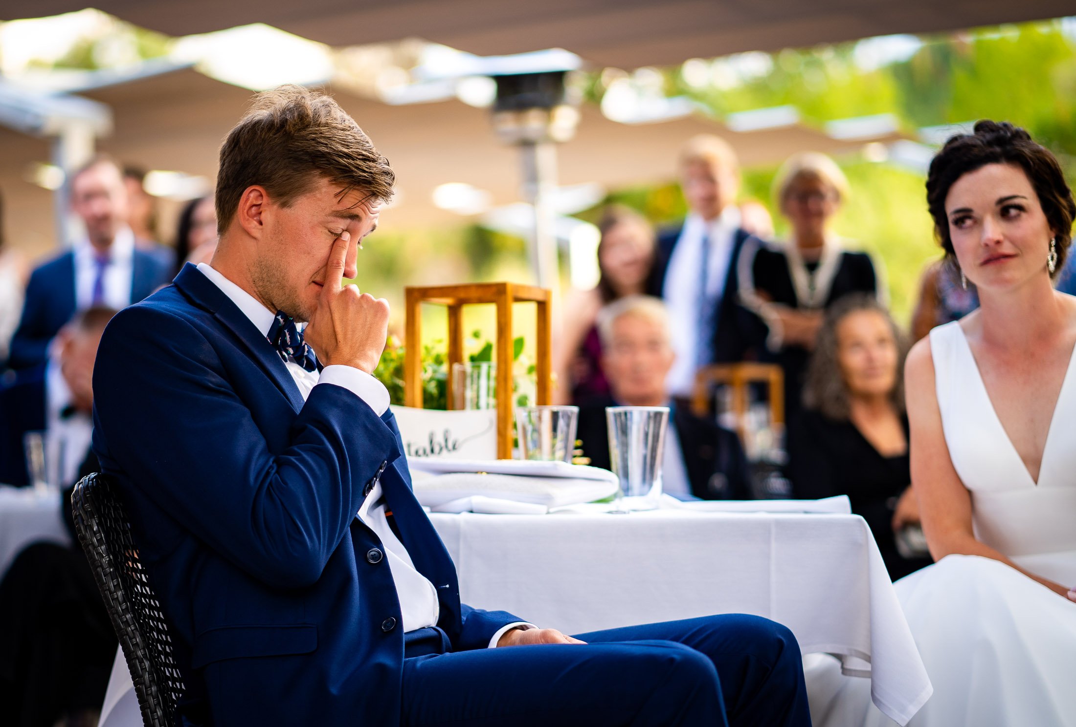 Bride and groom react to reception speeches while sitting on outdoor patio during the wedding reception, wedding, wedding photos, wedding photography, wedding photographer, wedding inspiration, wedding photo inspiration, wedding portraits, wedding ceremony, wedding reception, mountain wedding, Catholic Church wedding, Catholic Church wedding photos, Catholic Church wedding photography, Catholic Church wedding photographer, Catholic Church wedding inspiration, Catholic Church wedding venue, Steamboat Springs wedding, Steamboat Springs wedding photos, Steamboat Springs wedding photography, Steamboat Springs wedding photographer, Colorado wedding, Colorado wedding photos, Colorado wedding photography, Colorado wedding photographer, Colorado mountain wedding, Colorado wedding inspiration