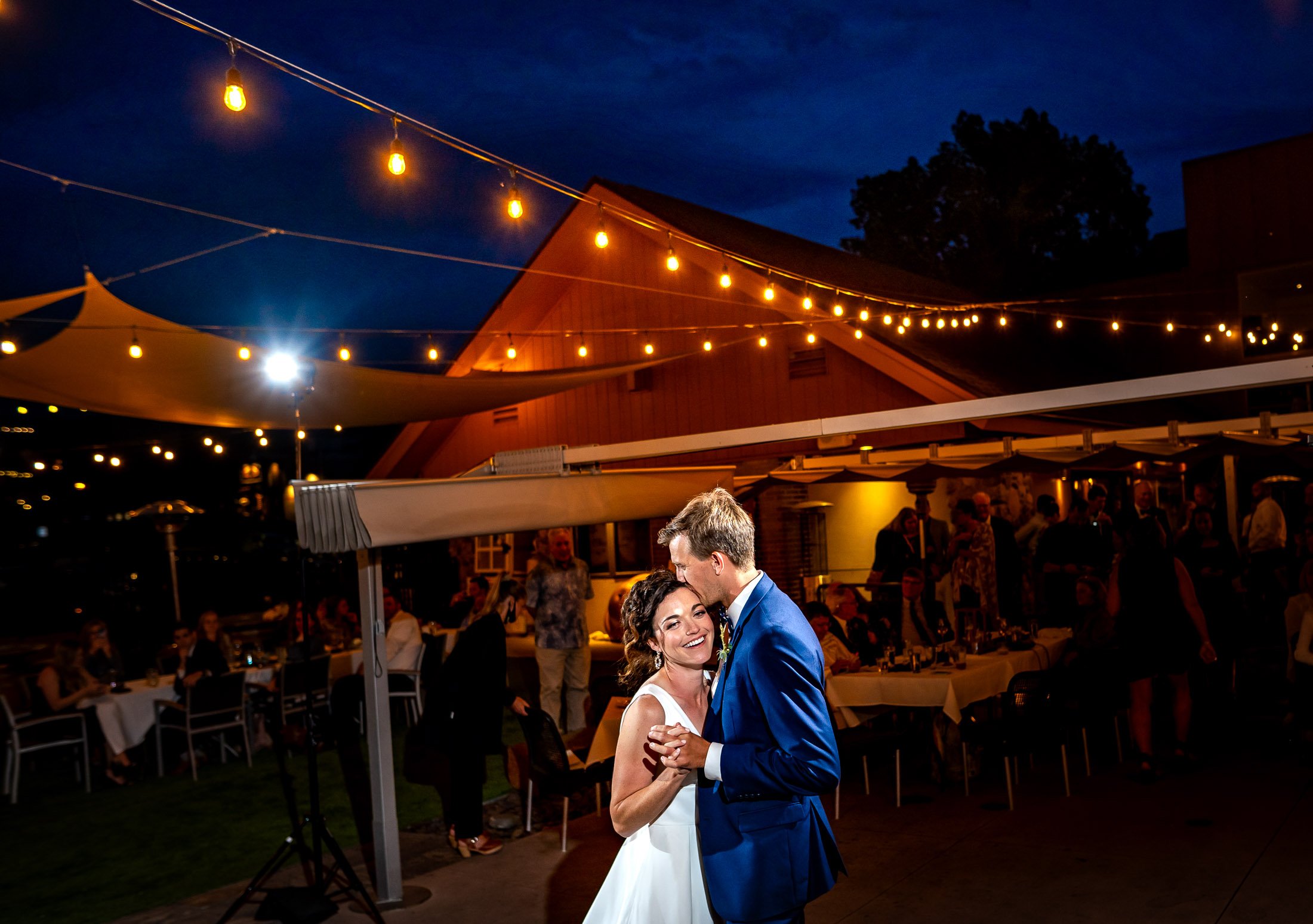 Bride and groom share their first dance on the outdoor patio under cafe lights at blue hour during their wedding reception, wedding, wedding photos, wedding photography, wedding photographer, wedding inspiration, wedding photo inspiration, wedding portraits, wedding ceremony, wedding reception, mountain wedding, Catholic Church wedding, Catholic Church wedding photos, Catholic Church wedding photography, Catholic Church wedding photographer, Catholic Church wedding inspiration, Catholic Church wedding venue, Steamboat Springs wedding, Steamboat Springs wedding photos, Steamboat Springs wedding photography, Steamboat Springs wedding photographer, Colorado wedding, Colorado wedding photos, Colorado wedding photography, Colorado wedding photographer, Colorado mountain wedding, Colorado wedding inspiration