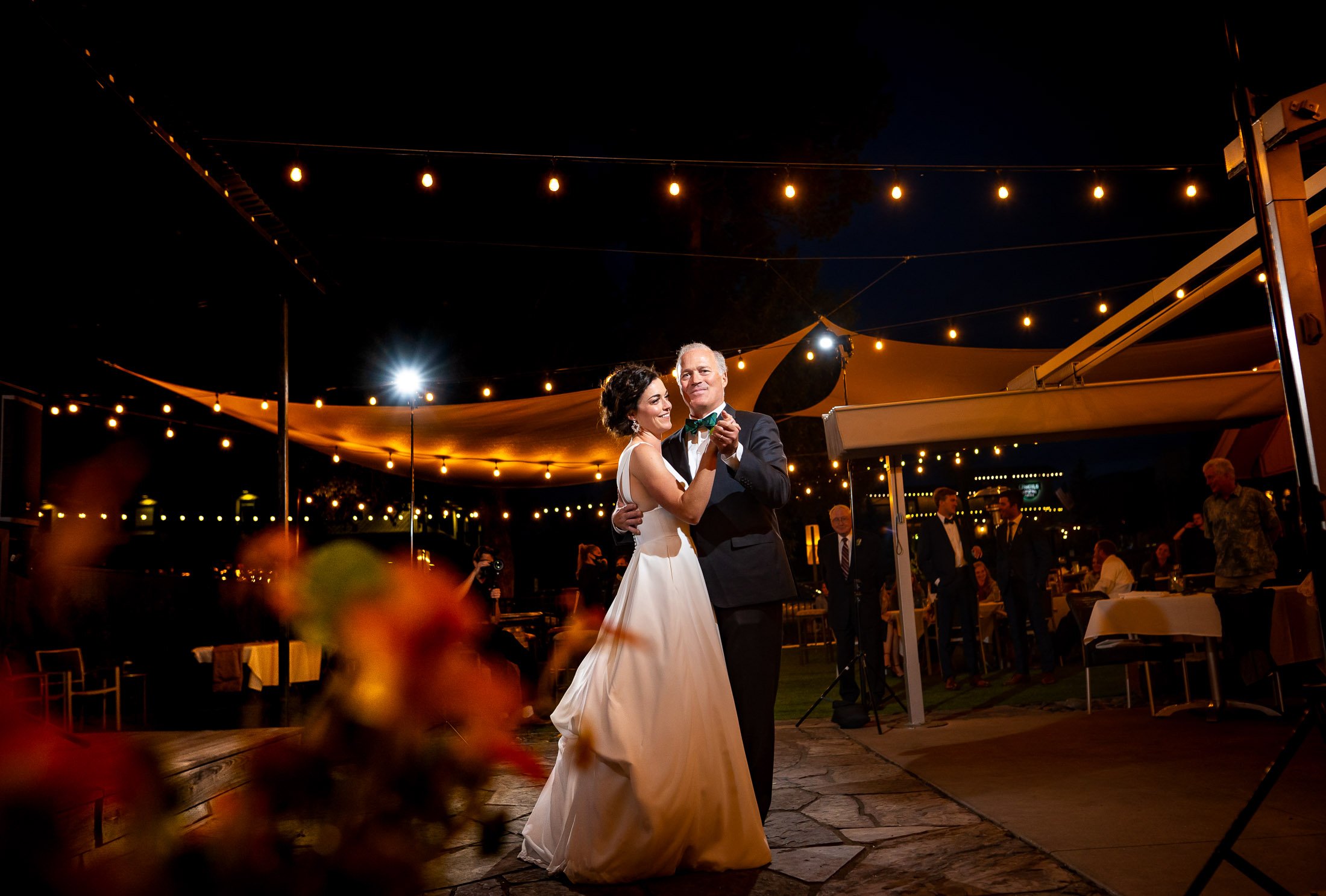 Bride shares a first dance with her father on the outdoor patio under cafe lights at blue hour during their wedding reception, wedding, wedding photos, wedding photography, wedding photographer, wedding inspiration, wedding photo inspiration, wedding portraits, wedding ceremony, wedding reception, mountain wedding, Catholic Church wedding, Catholic Church wedding photos, Catholic Church wedding photography, Catholic Church wedding photographer, Catholic Church wedding inspiration, Catholic Church wedding venue, Steamboat Springs wedding, Steamboat Springs wedding photos, Steamboat Springs wedding photography, Steamboat Springs wedding photographer, Colorado wedding, Colorado wedding photos, Colorado wedding photography, Colorado wedding photographer, Colorado mountain wedding, Colorado wedding inspiration