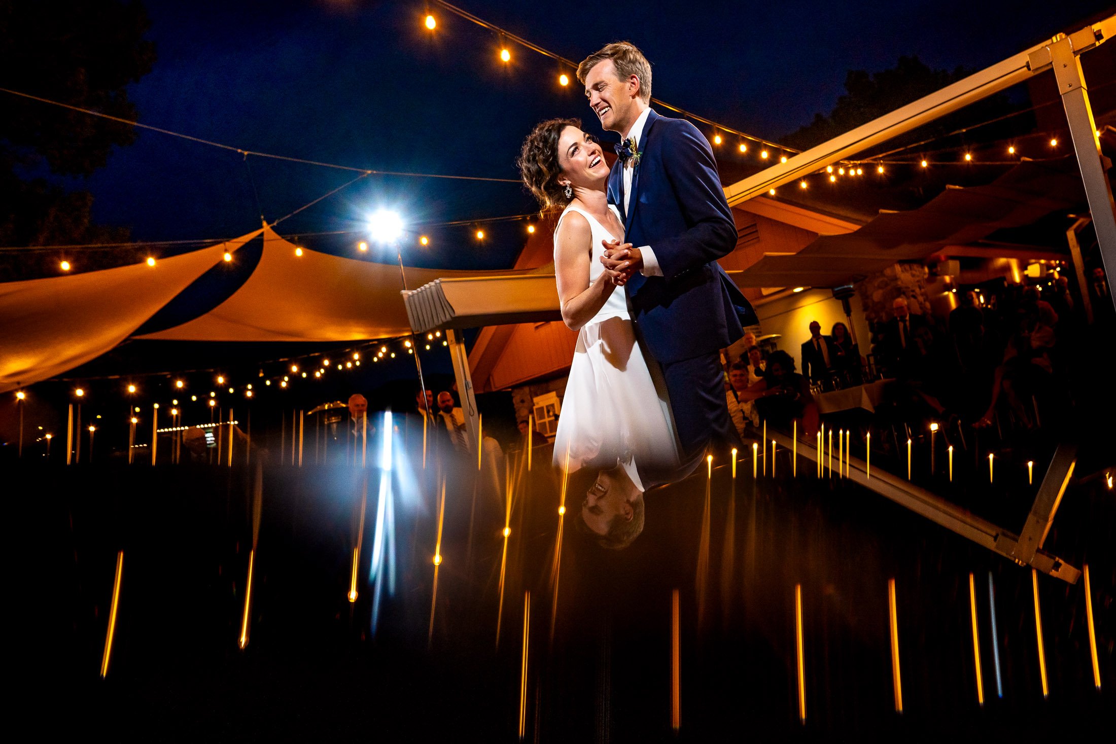 Bride and groom share their first dance on the outdoor patio under cafe lights at blue hour during their wedding reception, wedding, wedding photos, wedding photography, wedding photographer, wedding inspiration, wedding photo inspiration, wedding portraits, wedding ceremony, wedding reception, mountain wedding, Catholic Church wedding, Catholic Church wedding photos, Catholic Church wedding photography, Catholic Church wedding photographer, Catholic Church wedding inspiration, Catholic Church wedding venue, Steamboat Springs wedding, Steamboat Springs wedding photos, Steamboat Springs wedding photography, Steamboat Springs wedding photographer, Colorado wedding, Colorado wedding photos, Colorado wedding photography, Colorado wedding photographer, Colorado mountain wedding, Colorado wedding inspiration