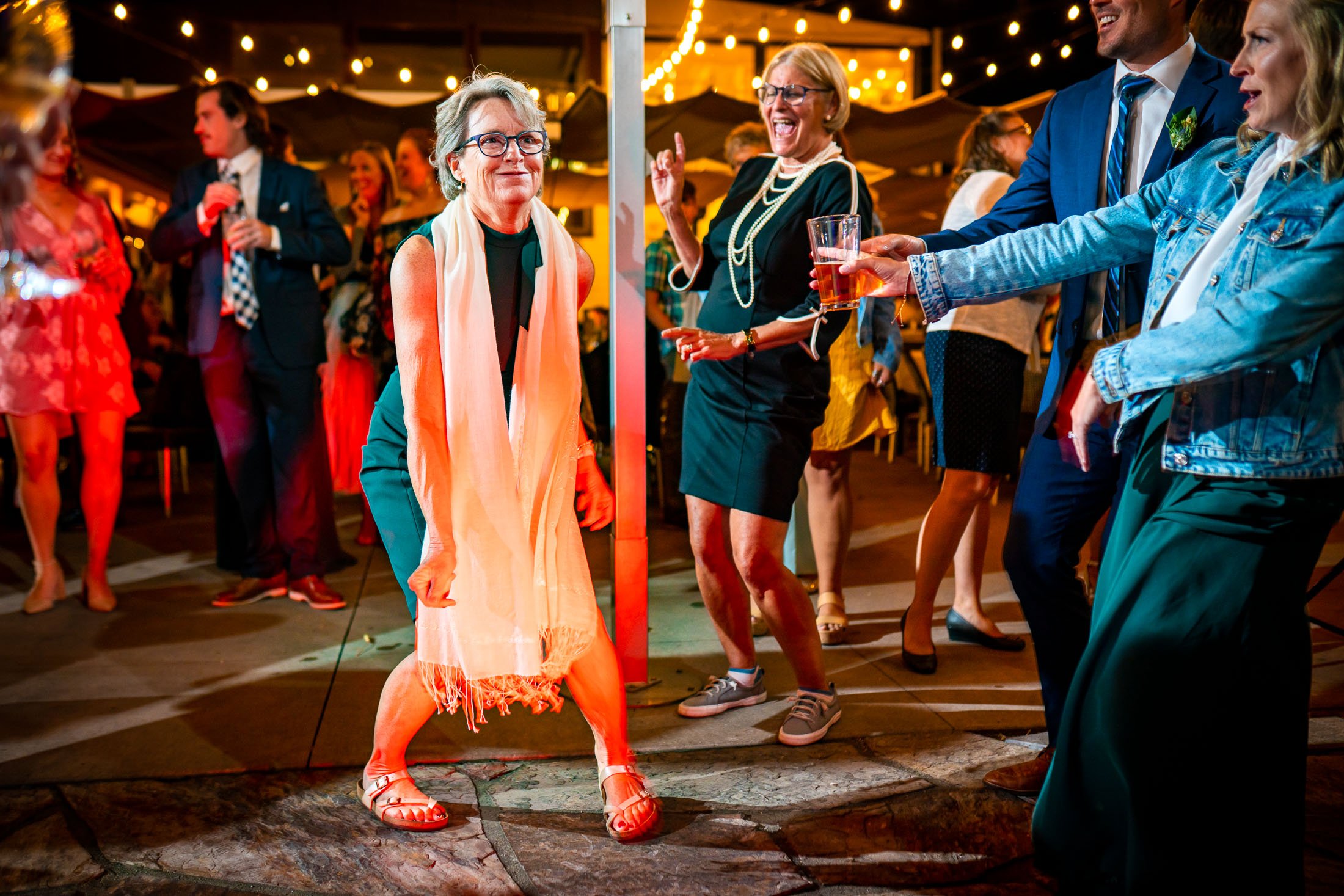 Guests dance to music on the outdoor patio under cafe lights during the wedding reception, wedding, wedding photos, wedding photography, wedding photographer, wedding inspiration, wedding photo inspiration, wedding portraits, wedding ceremony, wedding reception, mountain wedding, Catholic Church wedding, Catholic Church wedding photos, Catholic Church wedding photography, Catholic Church wedding photographer, Catholic Church wedding inspiration, Catholic Church wedding venue, Steamboat Springs wedding, Steamboat Springs wedding photos, Steamboat Springs wedding photography, Steamboat Springs wedding photographer, Colorado wedding, Colorado wedding photos, Colorado wedding photography, Colorado wedding photographer, Colorado mountain wedding, Colorado wedding inspiration