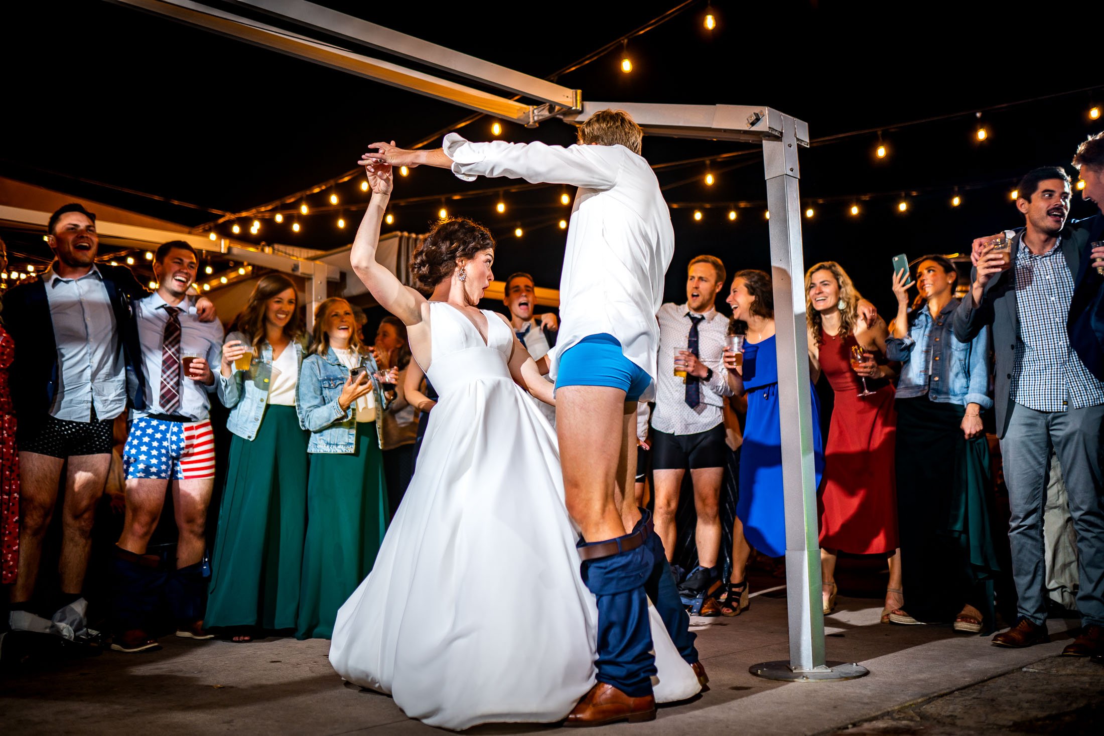 Bride and groom dance together while groom is wearing only his boxers on the outdoor patio under cafe lights during the wedding reception, wedding, wedding photos, wedding photography, wedding photographer, wedding inspiration, wedding photo inspiration, wedding portraits, wedding ceremony, wedding reception, mountain wedding, Catholic Church wedding, Catholic Church wedding photos, Catholic Church wedding photography, Catholic Church wedding photographer, Catholic Church wedding inspiration, Catholic Church wedding venue, Steamboat Springs wedding, Steamboat Springs wedding photos, Steamboat Springs wedding photography, Steamboat Springs wedding photographer, Colorado wedding, Colorado wedding photos, Colorado wedding photography, Colorado wedding photographer, Colorado mountain wedding, Colorado wedding inspiration