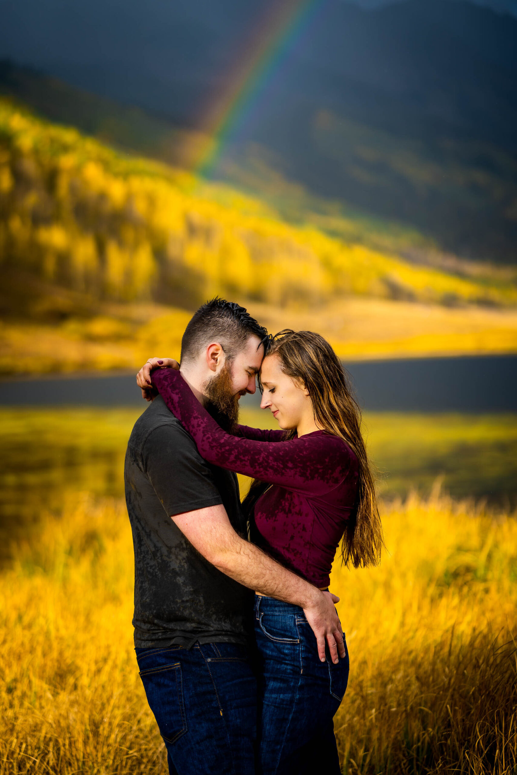 Engaged couple embraces for a portrait during a rainstorm with a double rainbow behind them arching over Piney Lake, Engagement Session, Engagement Photos, Engagement Photos Inspiration, Engagement Photography, Engagement Photographer, Fall Engagement Photos, Mountain Engagement Photos, Piney River Ranch engagement photos, Vail engagement session, Vail engagement photos, Vail engagement photography, Vail engagement photographer, Vail engagement inspiration, Colorado engagement session, Colorado engagement photos, Colorado engagement photography, Colorado engagement photographer, Colorado engagement inspiration