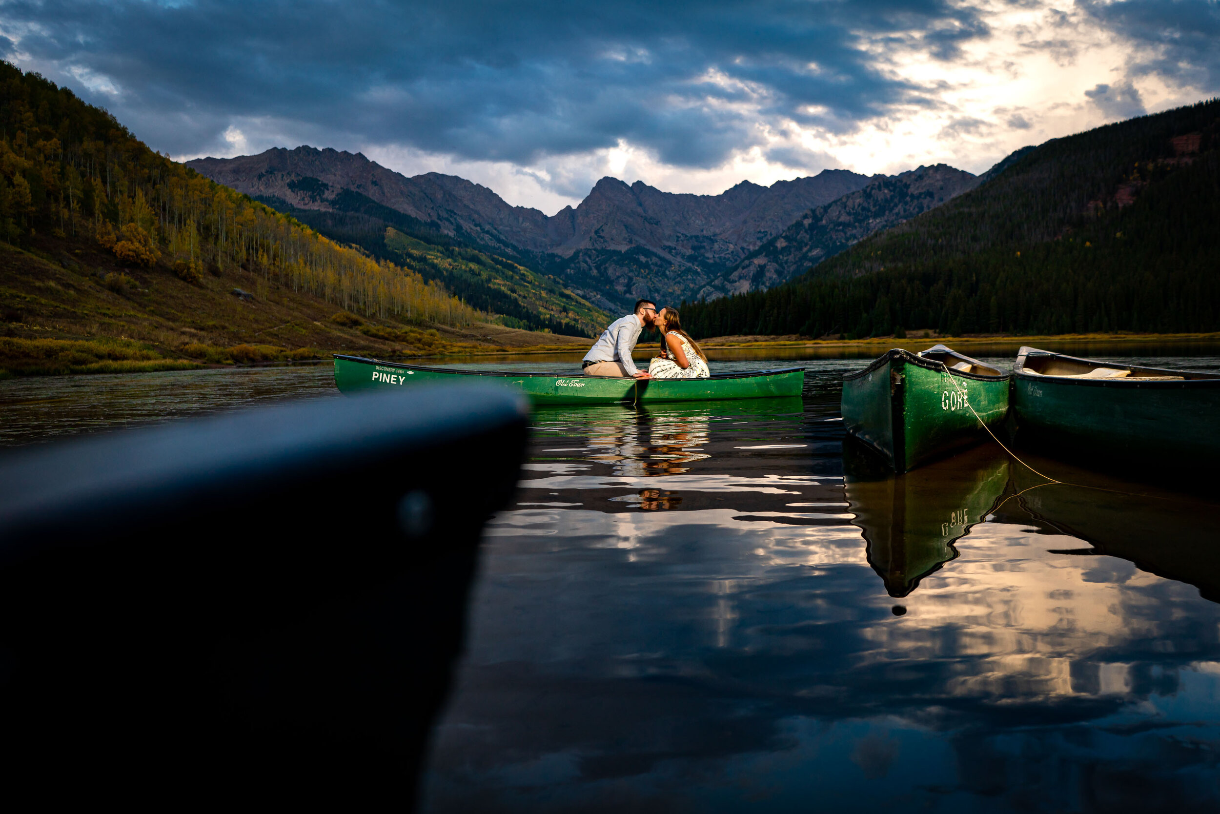 Engaged couple shares a kiss in a canoe on the lake during blue hour surrounded by water with the mountains in the background, Engagement Session, Engagement Photos, Engagement Photos Inspiration, Engagement Photography, Engagement Photographer, Fall Engagement Photos, Mountain Engagement Photos, Piney River Ranch engagement photos, Vail engagement session, Vail engagement photos, Vail engagement photography, Vail engagement photographer, Vail engagement inspiration, Colorado engagement session, Colorado engagement photos, Colorado engagement photography, Colorado engagement photographer, Colorado engagement inspiration