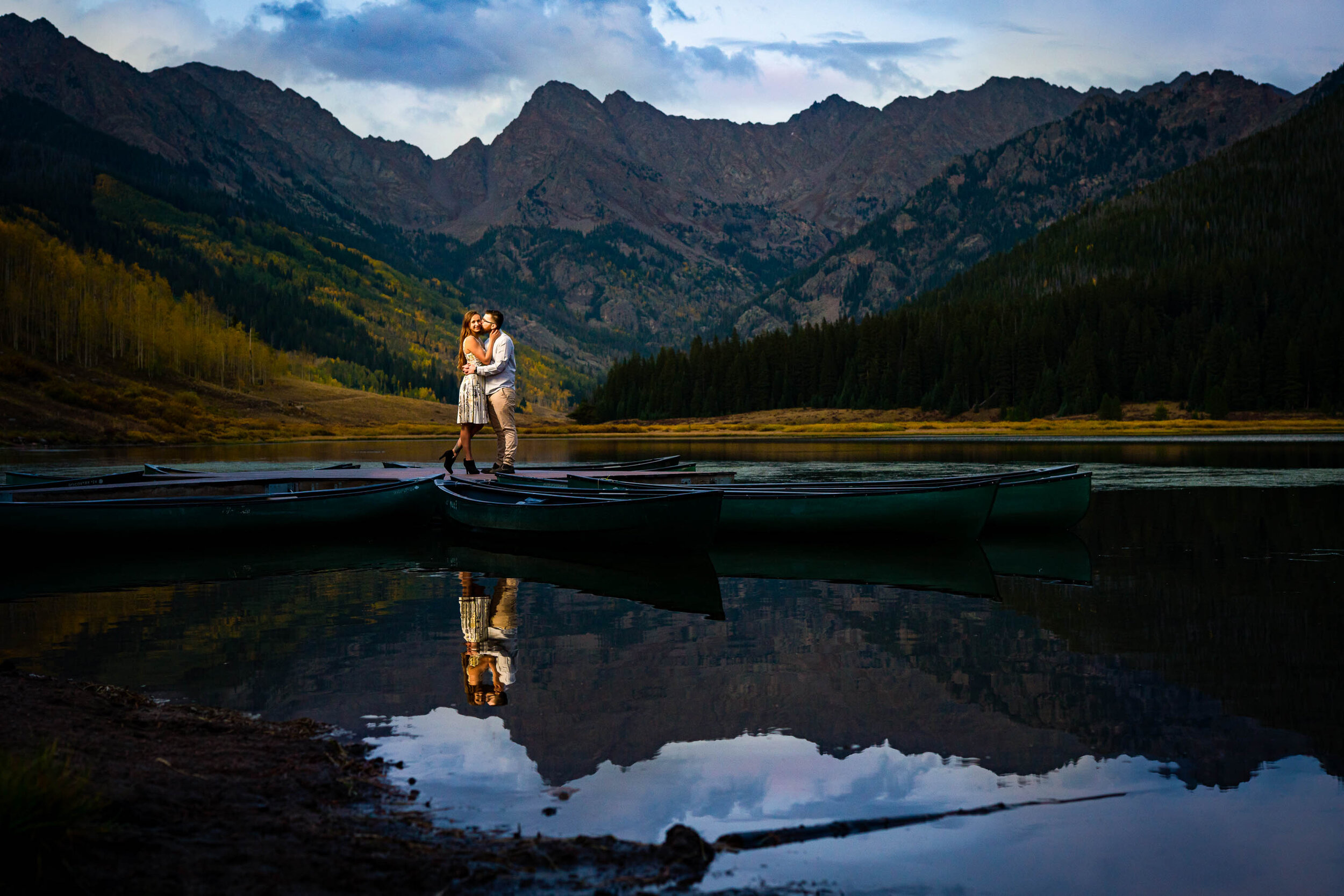 Engaged couple shares a kiss on the dock at blue hour surrounded by water with the mountains in the background, Engagement Session, Engagement Photos, Engagement Photos Inspiration, Engagement Photography, Engagement Photographer, Fall Engagement Photos, Mountain Engagement Photos, Piney River Ranch engagement photos, Vail engagement session, Vail engagement photos, Vail engagement photography, Vail engagement photographer, Vail engagement inspiration, Colorado engagement session, Colorado engagement photos, Colorado engagement photography, Colorado engagement photographer, Colorado engagement inspiration
