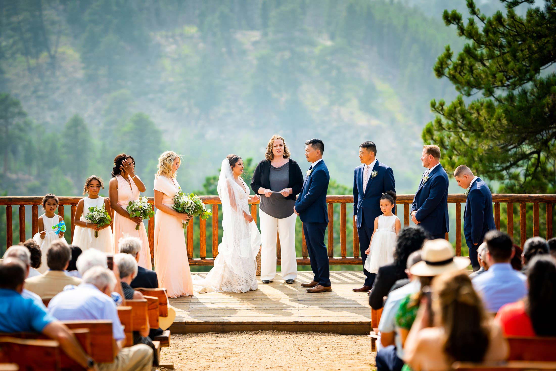 Bride and groom stand before their guests during their wedding ceremony in the mountains, wedding photos, wedding photography, wedding photographer, wedding inspiration, wedding photo inspiration, mountain wedding, YMCA of the Rockies wedding, YMCA of the Rockies wedding photos, YMCA of the Rockies wedding photography, YMCA of the Rockies wedding photographer, YMCA of the Rockies wedding inspiration, YMCA of the Rockies wedding venue, Estes Park wedding, Estes Park wedding photos, Estes Park wedding photography, Estes Park wedding photographer, Colorado wedding, Colorado wedding photos, Colorado wedding photography, Colorado wedding photographer, Colorado mountain wedding, Colorado wedding inspiration