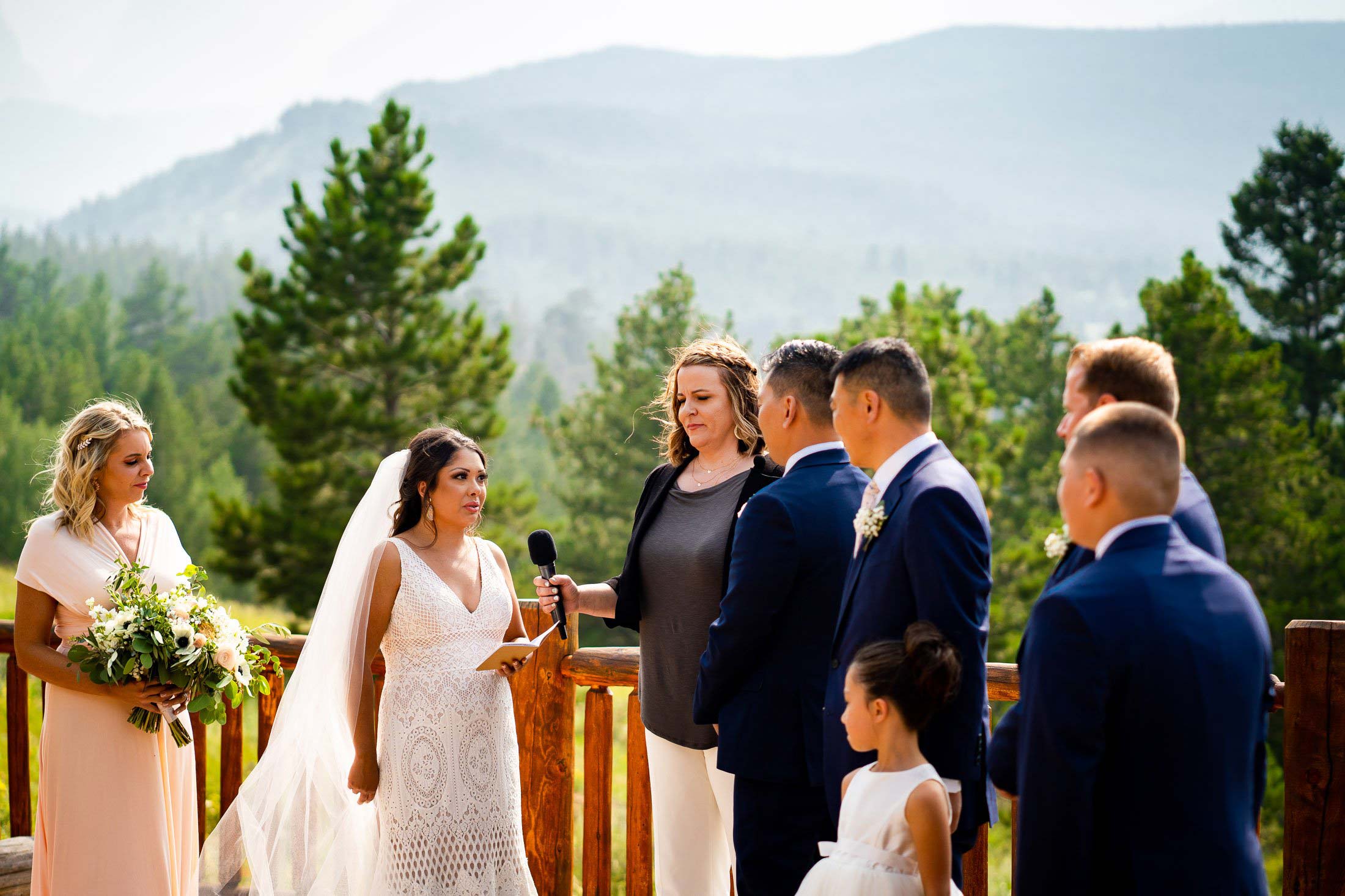 Bride reads her wedding vows during their wedding ceremony in the mountains as their wedding party stands by their side, wedding photos, wedding photography, wedding photographer, wedding inspiration, wedding photo inspiration, mountain wedding, YMCA of the Rockies wedding, YMCA of the Rockies wedding photos, YMCA of the Rockies wedding photography, YMCA of the Rockies wedding photographer, YMCA of the Rockies wedding inspiration, YMCA of the Rockies wedding venue, Estes Park wedding, Estes Park wedding photos, Estes Park wedding photography, Estes Park wedding photographer, Colorado wedding, Colorado wedding photos, Colorado wedding photography, Colorado wedding photographer, Colorado mountain wedding, Colorado wedding inspiration