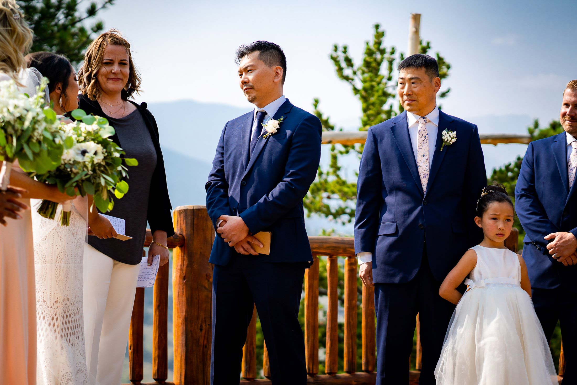 Groom listens as bride reads her wedding vows during their wedding ceremony in the mountains as their wedding party stands by their side, wedding photos, wedding photography, wedding photographer, wedding inspiration, wedding photo inspiration, mountain wedding, YMCA of the Rockies wedding, YMCA of the Rockies wedding photos, YMCA of the Rockies wedding photography, YMCA of the Rockies wedding photographer, YMCA of the Rockies wedding inspiration, YMCA of the Rockies wedding venue, Estes Park wedding, Estes Park wedding photos, Estes Park wedding photography, Estes Park wedding photographer, Colorado wedding, Colorado wedding photos, Colorado wedding photography, Colorado wedding photographer, Colorado mountain wedding, Colorado wedding inspiration