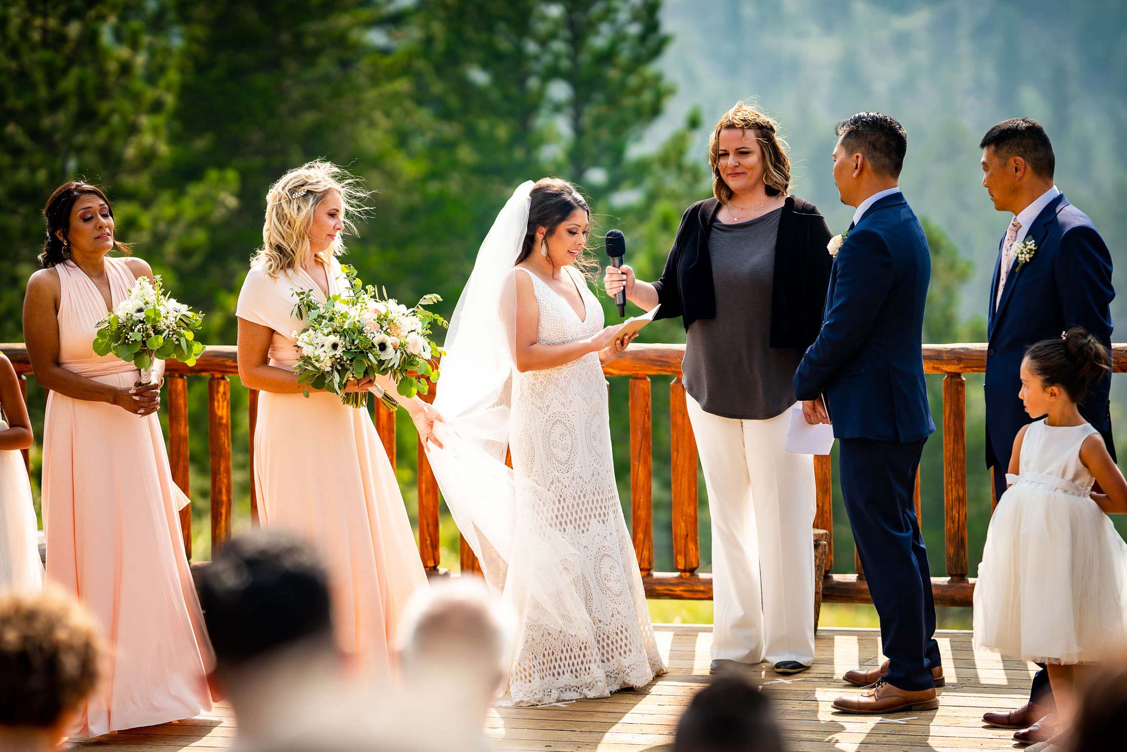 Bride reads her wedding vows during their wedding ceremony in the mountains as their wedding party stands by their side, wedding photos, wedding photography, wedding photographer, wedding inspiration, wedding photo inspiration, mountain wedding, YMCA of the Rockies wedding, YMCA of the Rockies wedding photos, YMCA of the Rockies wedding photography, YMCA of the Rockies wedding photographer, YMCA of the Rockies wedding inspiration, YMCA of the Rockies wedding venue, Estes Park wedding, Estes Park wedding photos, Estes Park wedding photography, Estes Park wedding photographer, Colorado wedding, Colorado wedding photos, Colorado wedding photography, Colorado wedding photographer, Colorado mountain wedding, Colorado wedding inspiration