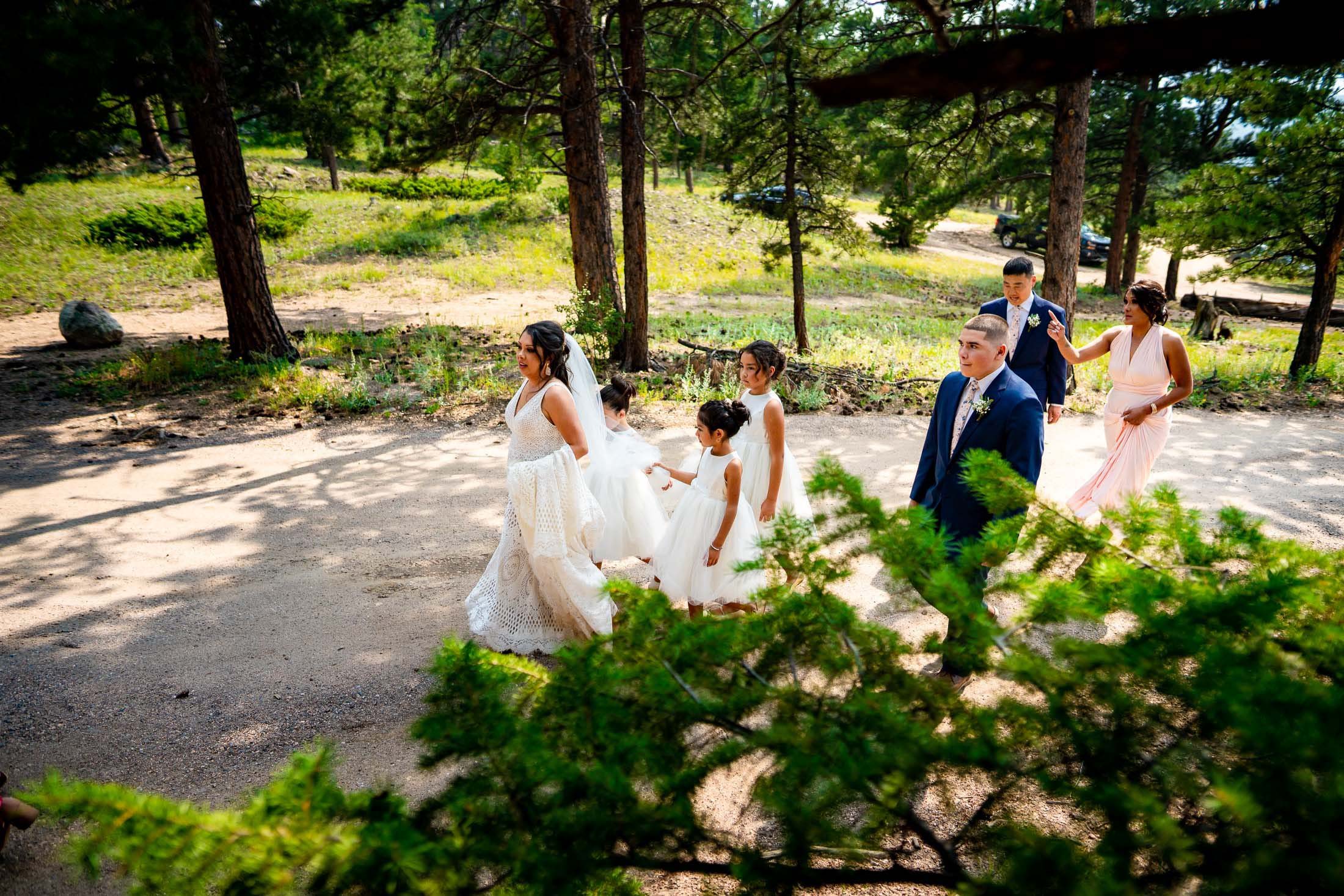 Bride walks with the wedding party in the forest after the wedding ceremony, wedding photos, wedding photography, wedding photographer, wedding inspiration, wedding photo inspiration, mountain wedding, YMCA of the Rockies wedding, YMCA of the Rockies wedding photos, YMCA of the Rockies wedding photography, YMCA of the Rockies wedding photographer, YMCA of the Rockies wedding inspiration, YMCA of the Rockies wedding venue, Estes Park wedding, Estes Park wedding photos, Estes Park wedding photography, Estes Park wedding photographer, Colorado wedding, Colorado wedding photos, Colorado wedding photography, Colorado wedding photographer, Colorado mountain wedding, Colorado wedding inspiration