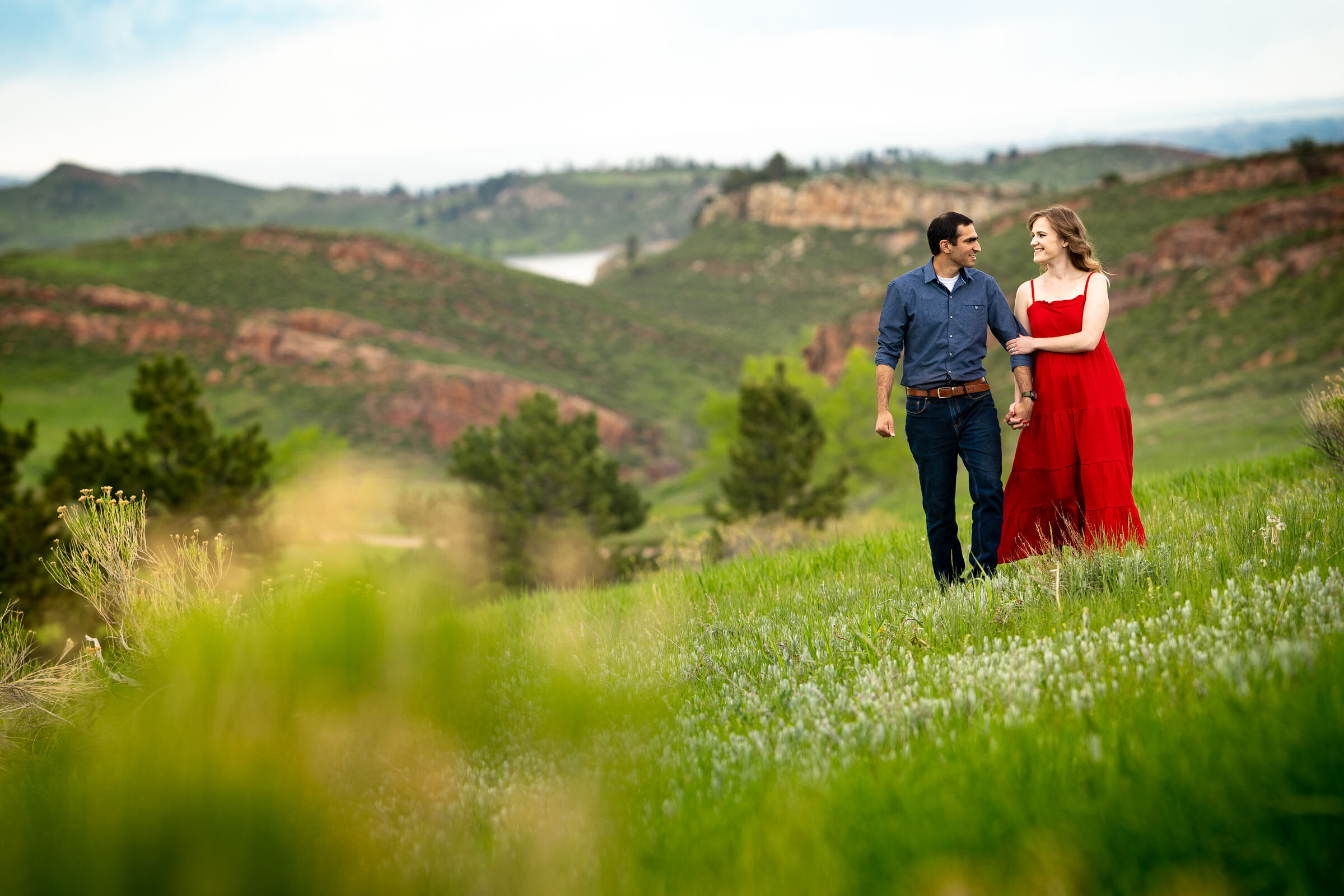 Engaged couple embraces in a luscious green landscape of rolling foothills during golden hour, Engagement Photos, Engagement Photo Inspiration, Engagement Photography, Engagement Photographer, Spring Engagement Photos, Fort Collins Engagement Photos, Fort Collins engagement photos, Fort Collins engagement photography, Fort Collins engagement photographer, Colorado engagement photos, Colorado engagement photography, Colorado engagement inspiration, Horsetooth Reservoir Engagement
