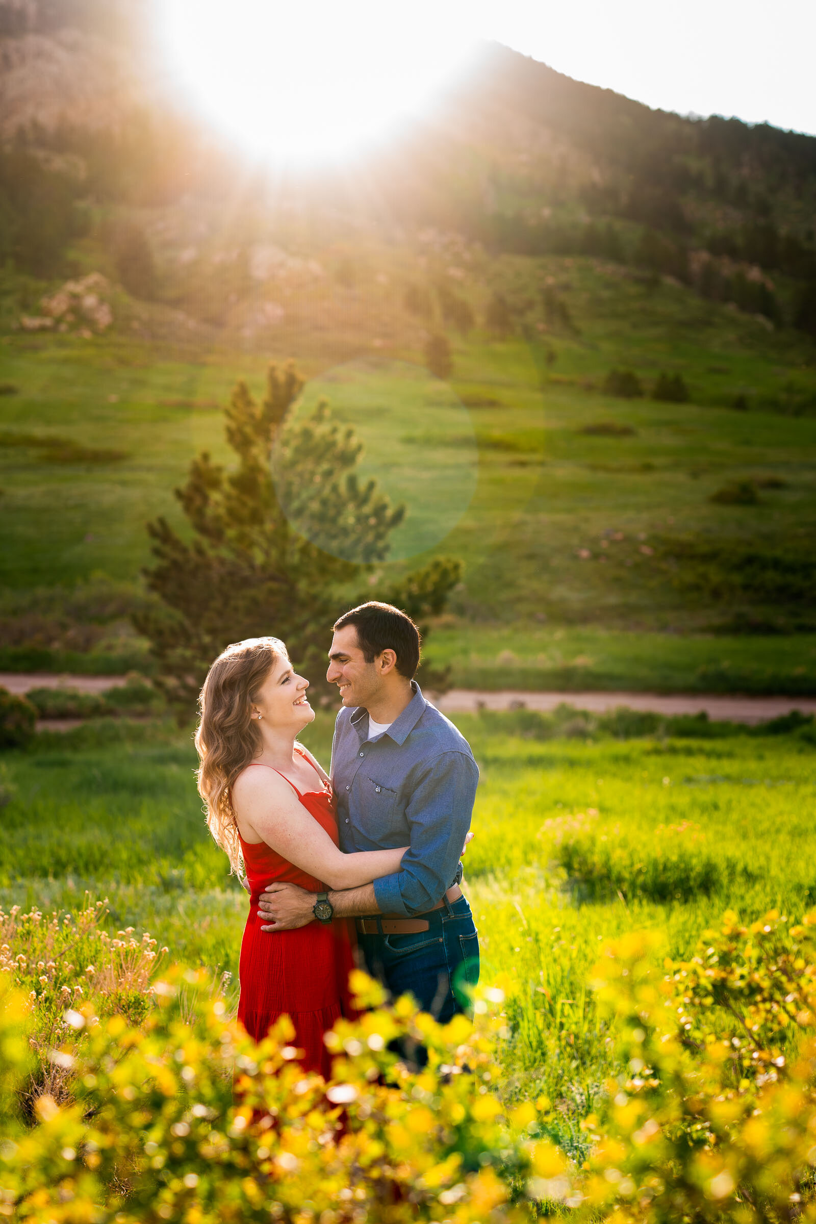 Engaged couple embraces in a luscious green landscape of rolling foothills during golden hour, Engagement Photos, Engagement Photo Inspiration, Engagement Photography, Engagement Photographer, Spring Engagement Photos, Fort Collins Engagement Photos, Fort Collins engagement photos, Fort Collins engagement photography, Fort Collins engagement photographer, Colorado engagement photos, Colorado engagement photography, Colorado engagement inspiration, Horsetooth Reservoir Engagement