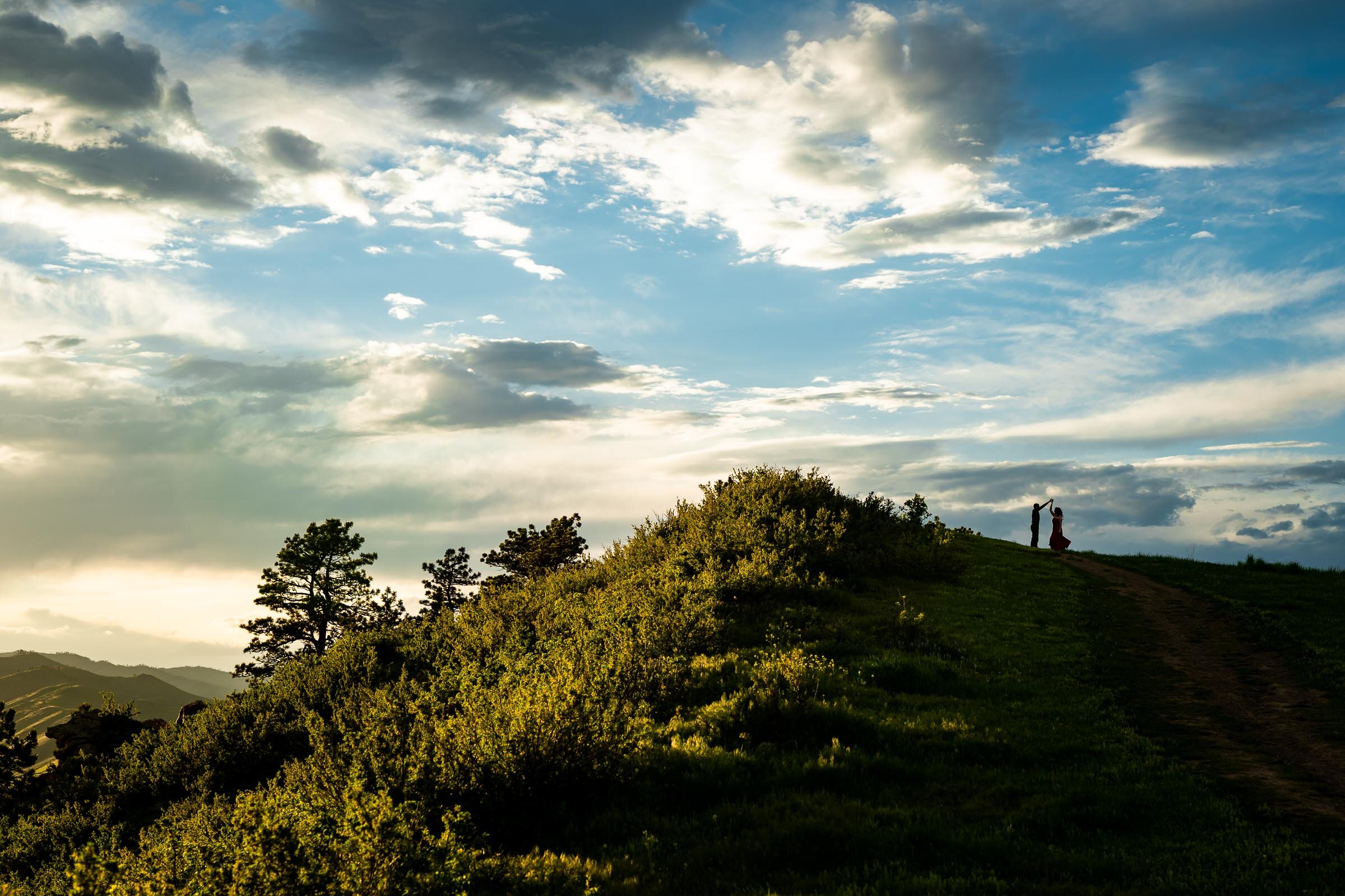 Engaged couple are silhouetted in a green foothill landscape during golden hour by the water, Engagement Photos, Engagement Photo Inspiration, Engagement Photography, Engagement Photographer, Spring Engagement Photos, Fort Collins Engagement Photos, Fort Collins engagement photos, Fort Collins engagement photography, Fort Collins engagement photographer, Colorado engagement photos, Colorado engagement photography, Colorado engagement inspiration, Horsetooth Reservoir Engagement