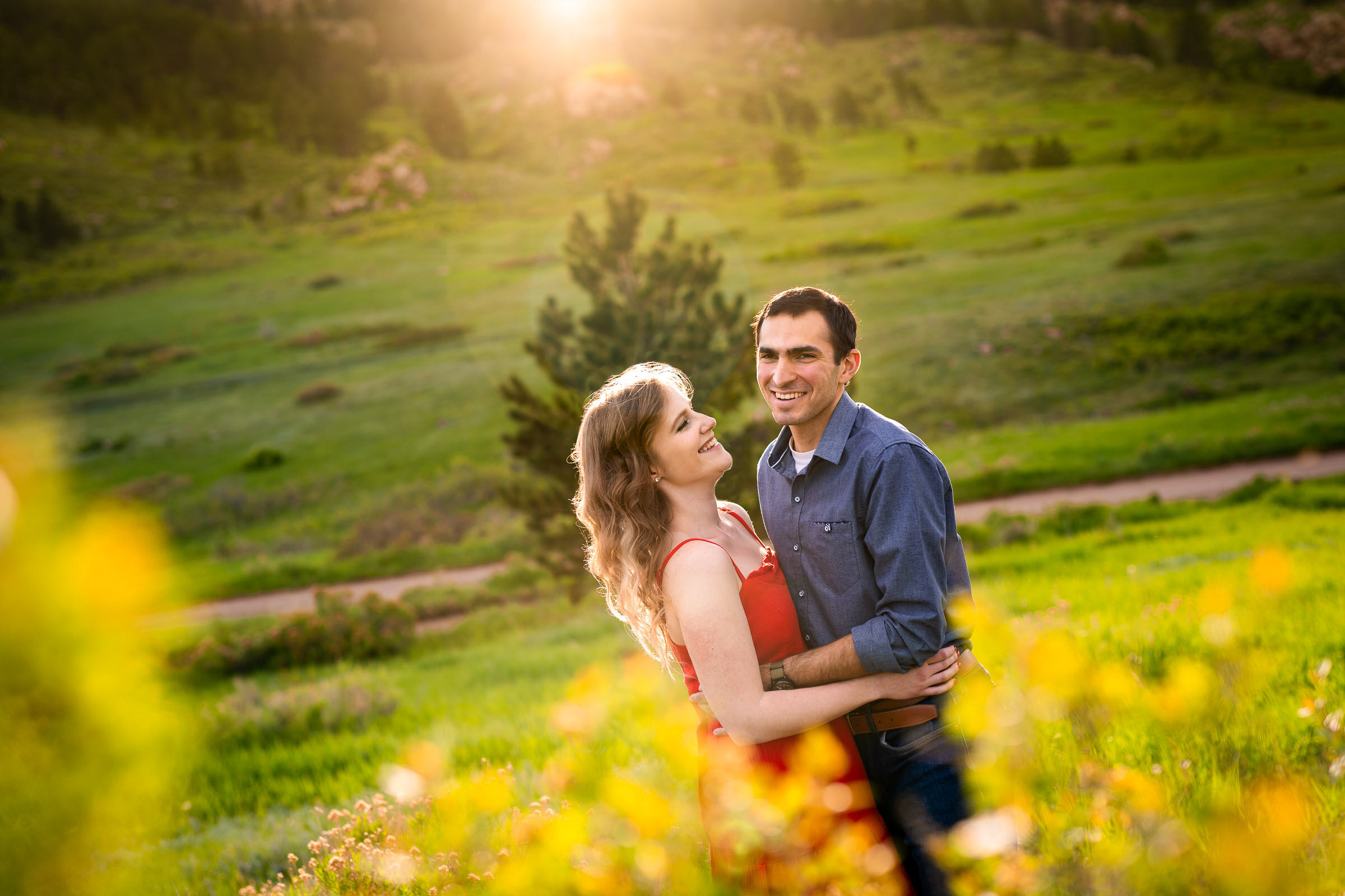 Engaged couple embraces in a luscious green landscape of rolling foothills during golden hour, Engagement Photos, Engagement Photo Inspiration, Engagement Photography, Engagement Photographer, Spring Engagement Photos, Fort Collins Engagement Photos, Fort Collins engagement photos, Fort Collins engagement photography, Fort Collins engagement photographer, Colorado engagement photos, Colorado engagement photography, Colorado engagement inspiration, Horsetooth Reservoir Engagement