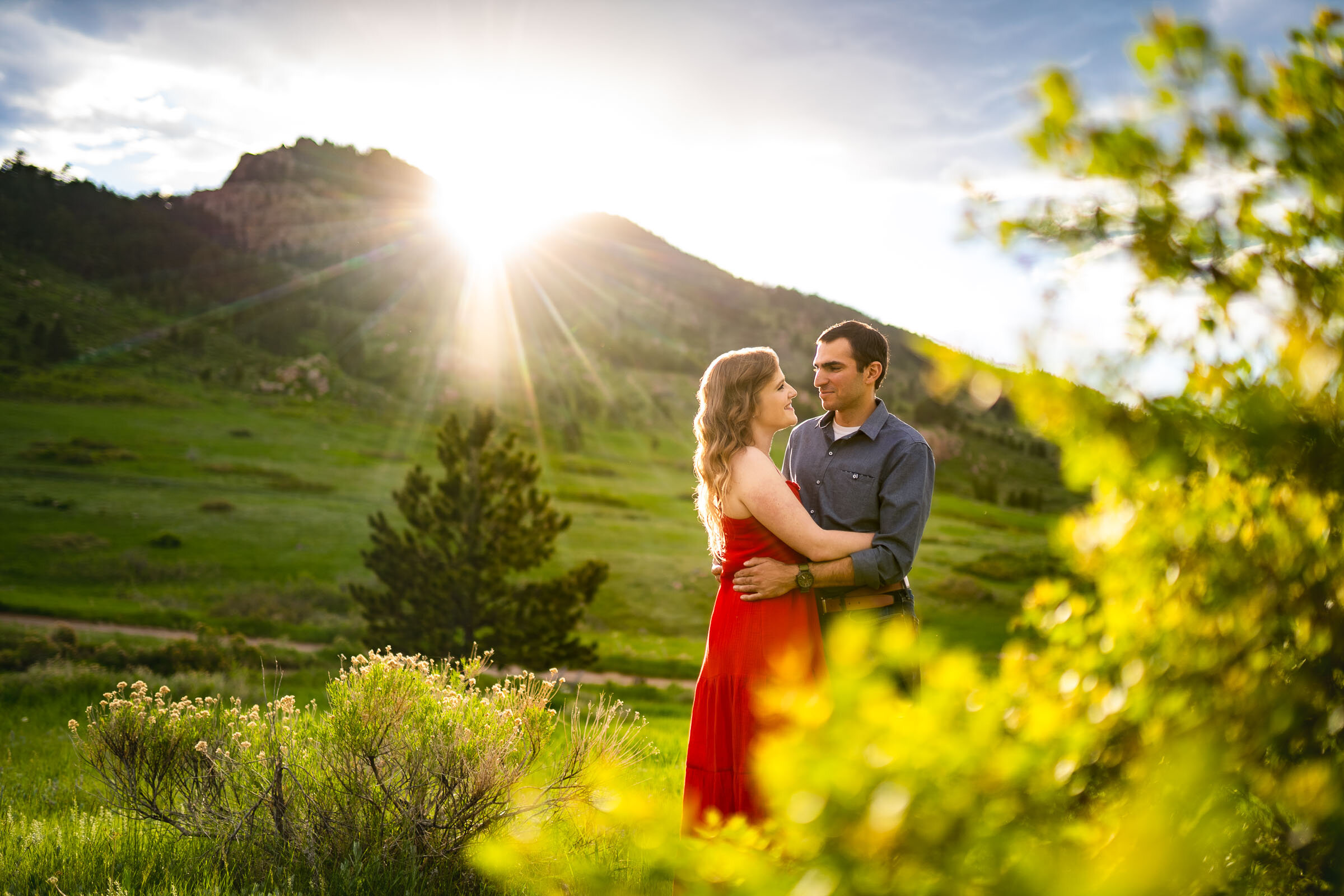 Engaged couple embraces in a luscious green landscape of rolling foothills during golden hour, Engagement Photos, Engagement Photo Inspiration, Engagement Photography, Engagement Photographer, Spring Engagement Photos, Fort Collins Engagement Photos, Fort Collins engagement photos, Fort Collins engagement photography, Fort Collins engagement photographer, Colorado engagement photos, Colorado engagement photography, Colorado engagement inspiration, Horsetooth Reservoir Engagement
