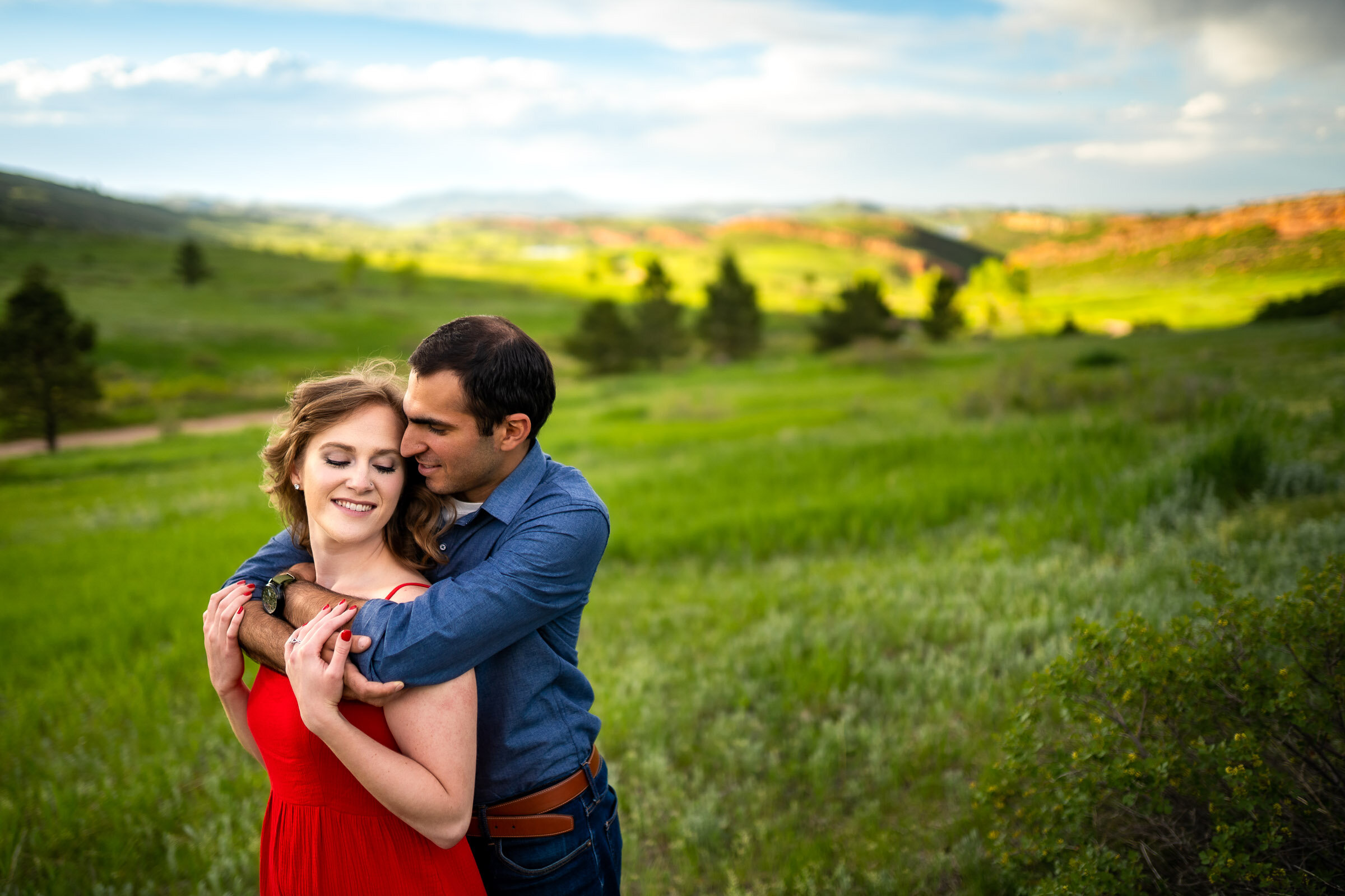 Engaged couple embraces in a luscious green landscape of rolling foothills during golden hour, Engagement Photos, Engagement Photo Inspiration, Engagement Photography, Engagement Photographer, Spring Engagement Photos, Fort Collins Engagement Photos, Fort Collins engagement photos, Fort Collins engagement photography, Fort Collins engagement photographer, Colorado engagement photos, Colorado engagement photography, Colorado engagement inspiration, Horsetooth Reservoir Engagement
