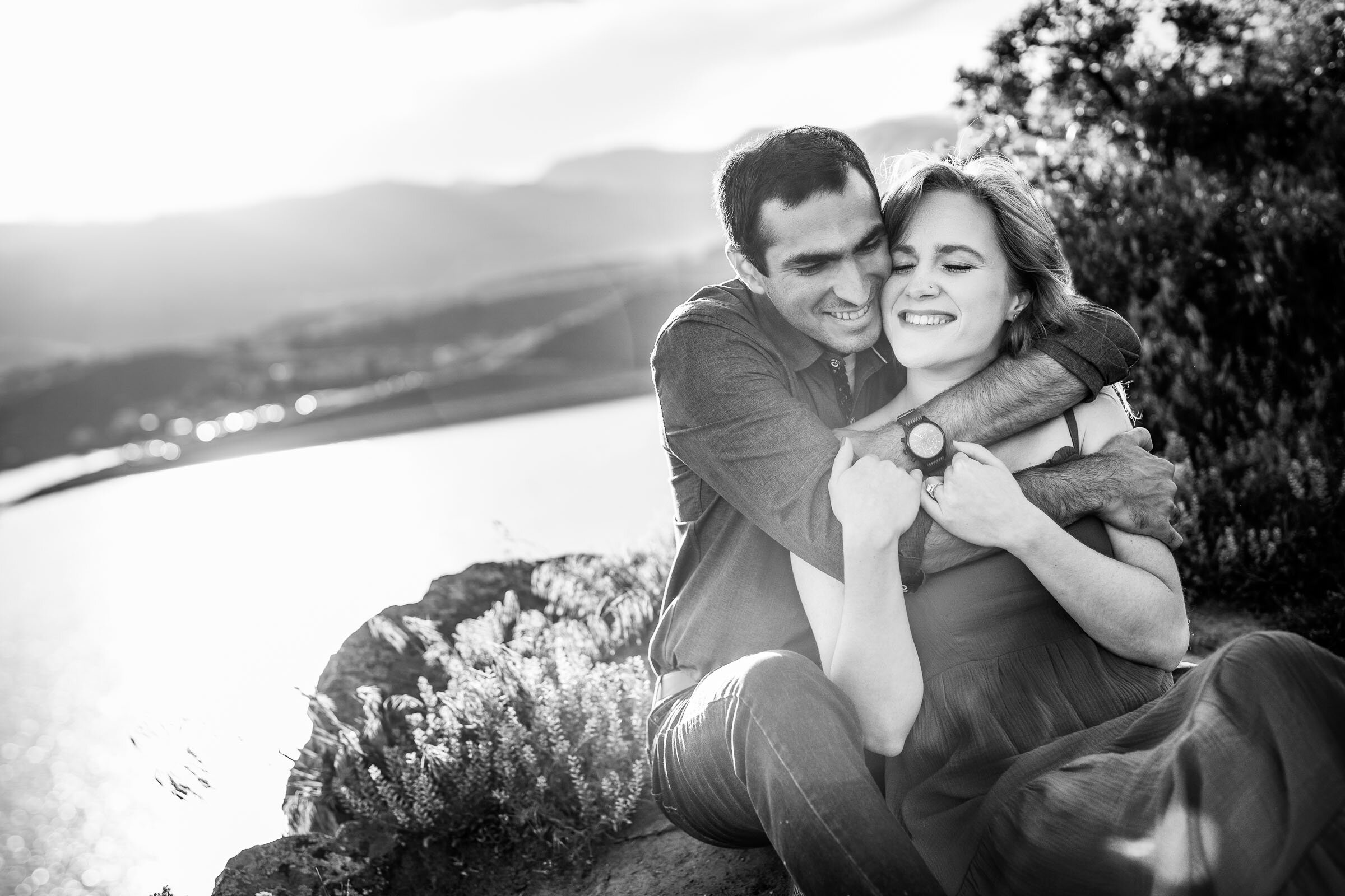 Engaged couple embraces in a luscious green landscape in the foothills during golden hour by the water, Engagement Photos, Engagement Photo Inspiration, Engagement Photography, Engagement Photographer, Spring Engagement Photos, Fort Collins Engagement Photos, Fort Collins engagement photos, Fort Collins engagement photography, Fort Collins engagement photographer, Colorado engagement photos, Colorado engagement photography, Colorado engagement inspiration, Horsetooth Reservoir Engagement
