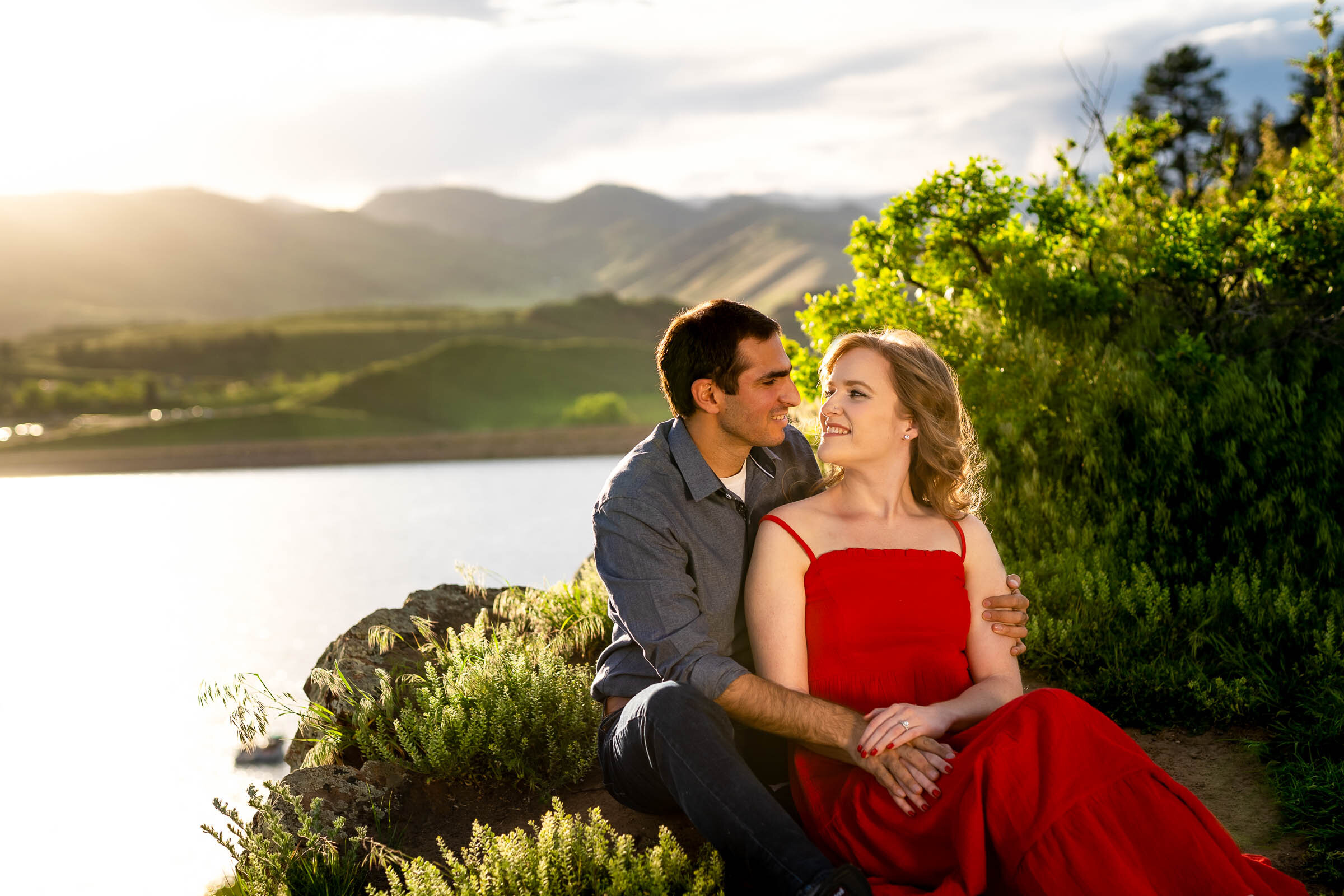 Engaged couple embraces in a luscious green landscape in the foothills during golden hour by the water, Engagement Photos, Engagement Photo Inspiration, Engagement Photography, Engagement Photographer, Spring Engagement Photos, Fort Collins Engagement Photos, Fort Collins engagement photos, Fort Collins engagement photography, Fort Collins engagement photographer, Colorado engagement photos, Colorado engagement photography, Colorado engagement inspiration, Horsetooth Reservoir Engagement