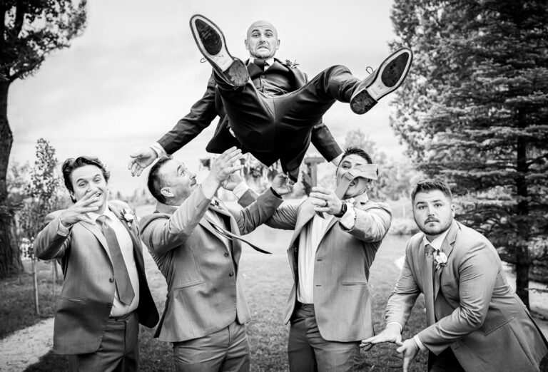 Groomsmen toss groom in the air during a backyard wedding in Fort Collins, Colorado