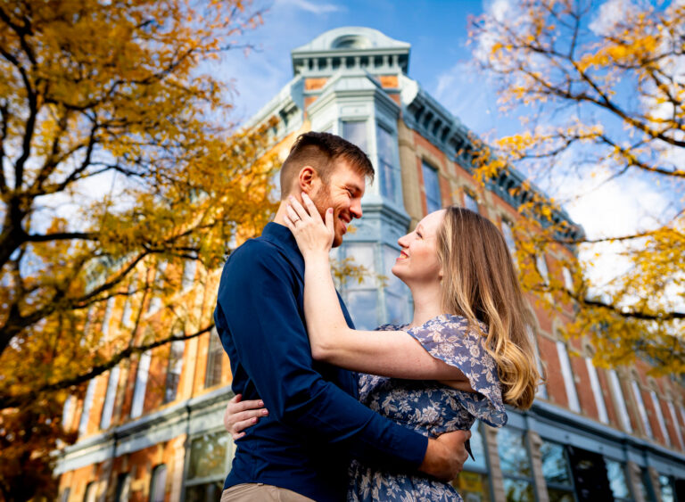 A couple embraces in front of historic building in Fort Collins, Colorado