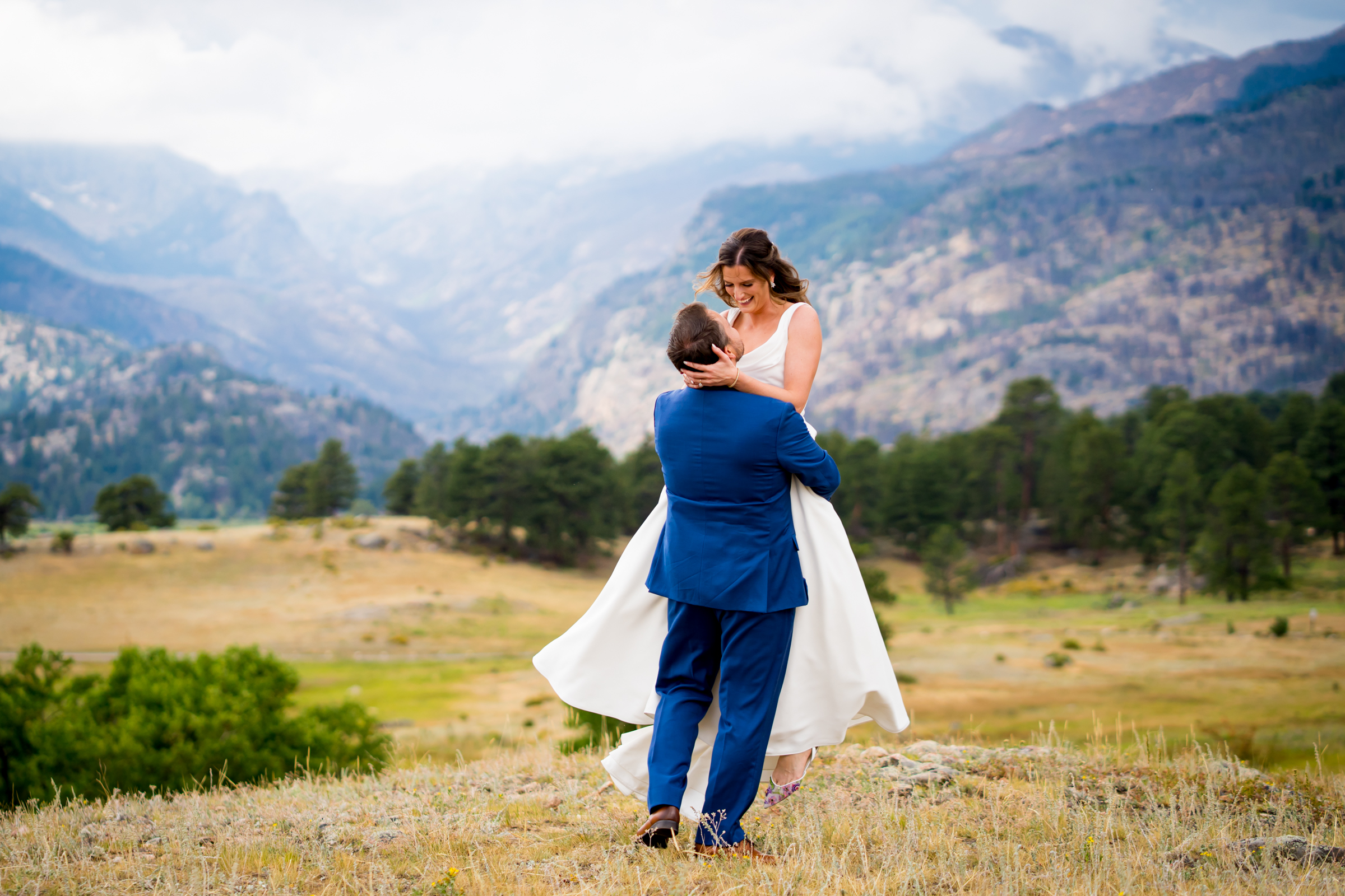Bride and groom pose for newlywed portraits at Rocky Mountain National Park with the mountains and meadows in the distance