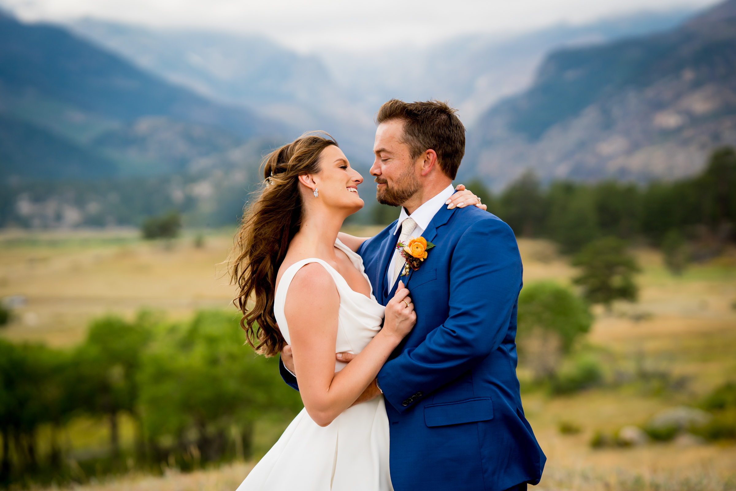 Bride and groom pose for newlywed portraits at Rocky Mountain National Park with the mountains and meadows in the distance