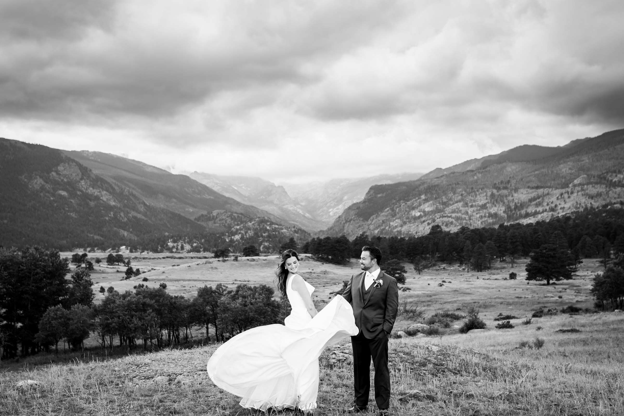Bride and groom pose for newlywed portraits at Rocky Mountain National Park with the mountains and meadows in the distance