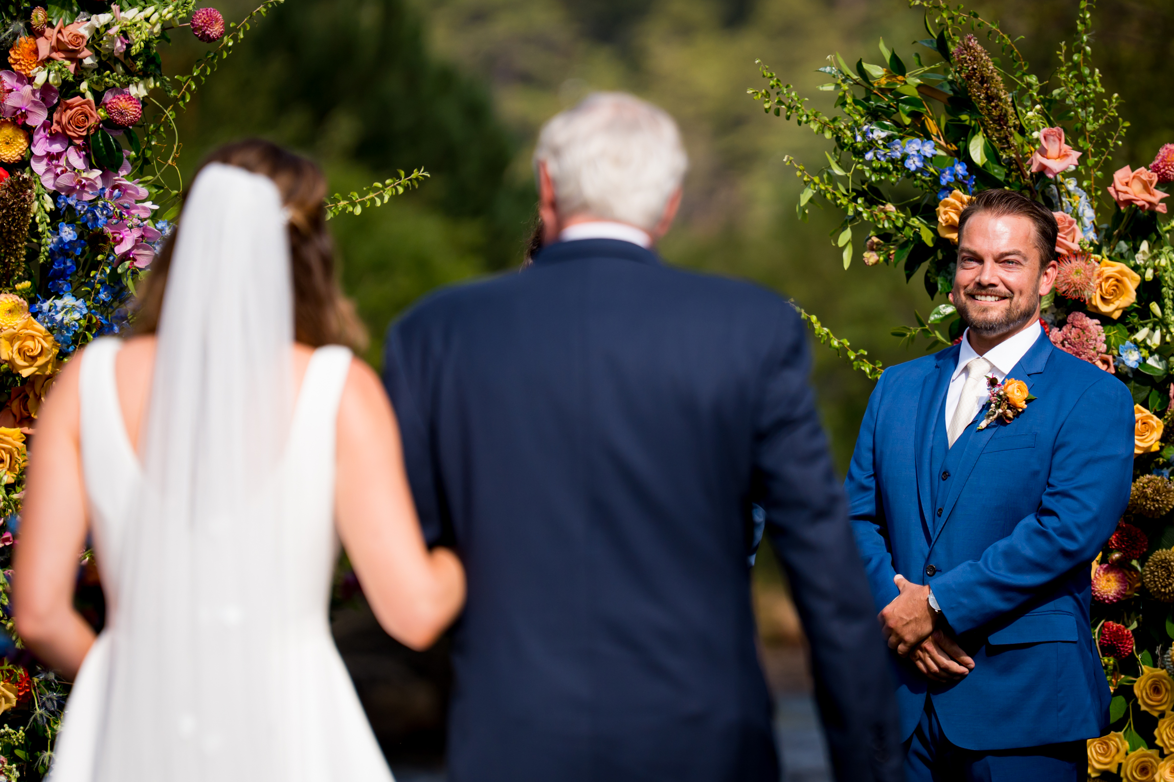 Groom smiles as the bride walks down the aisle during the processional
