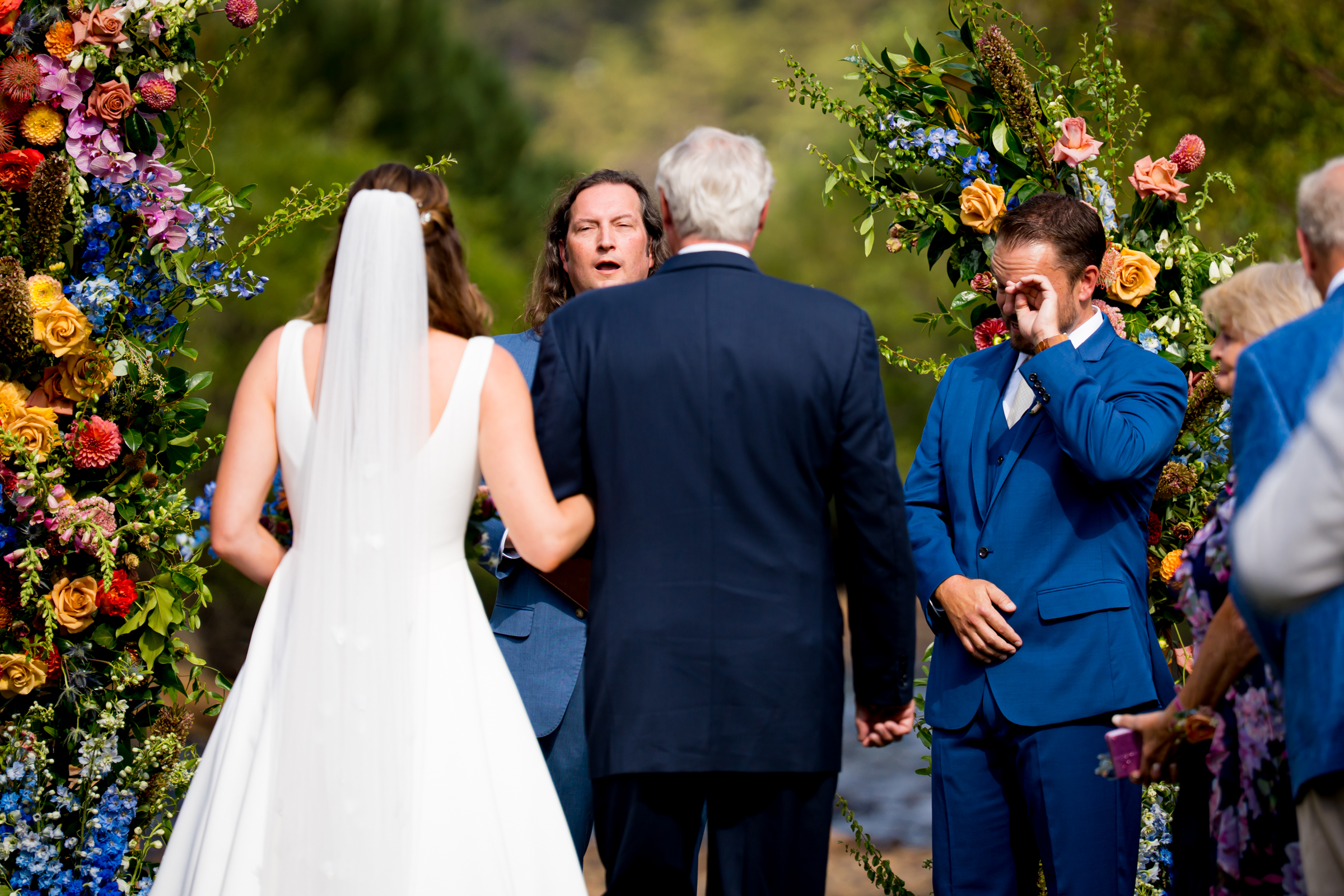 Groom wipes away a tear as the bride walks down the aisle during the processional
